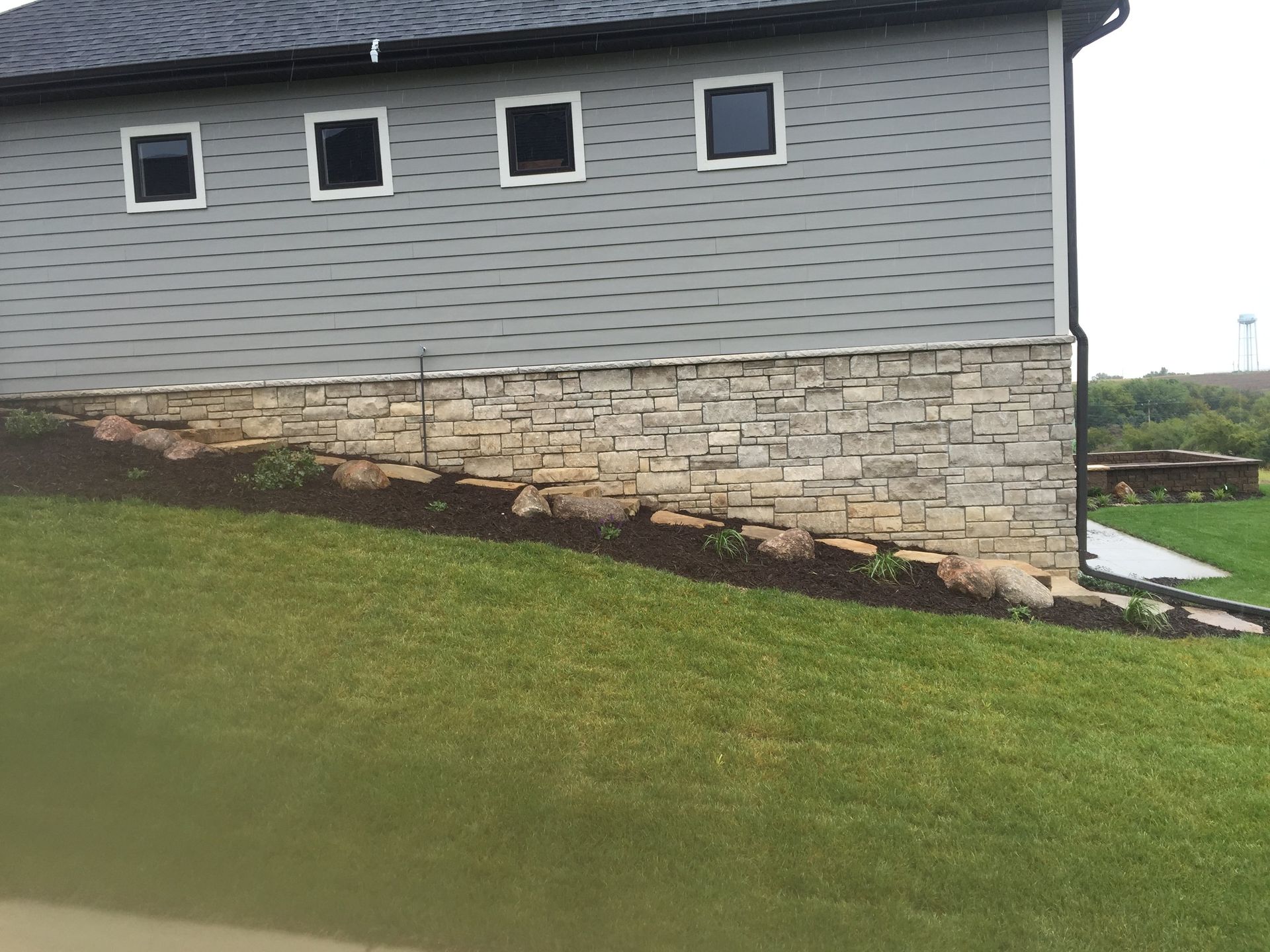 A house with a stone wall on the side of it.