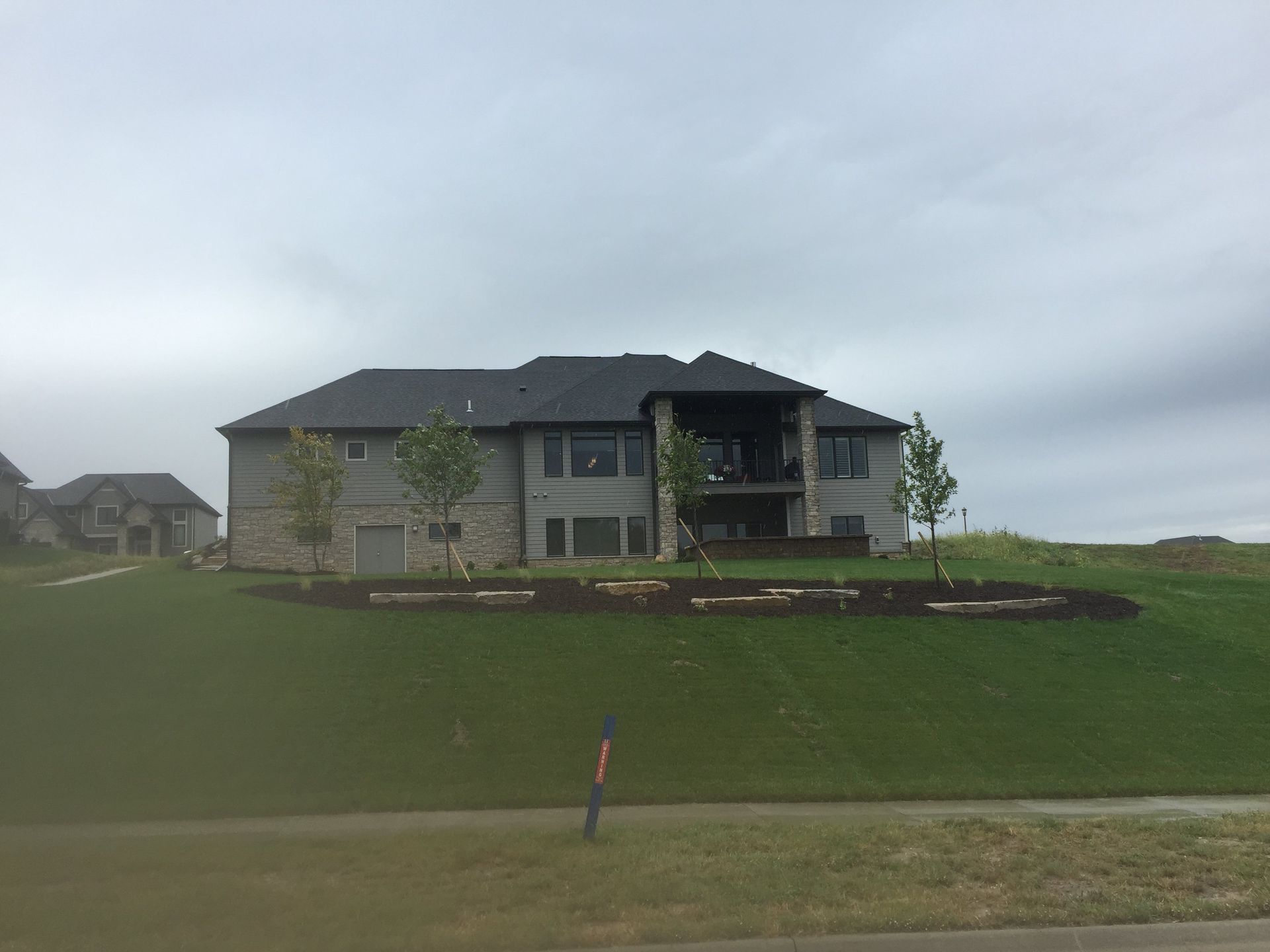 A large house is sitting on top of a grassy hill.