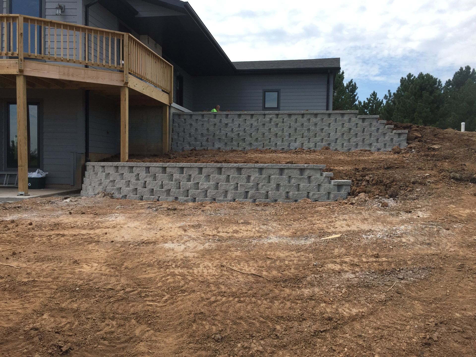 A house with a deck and a stone wall in front of it.