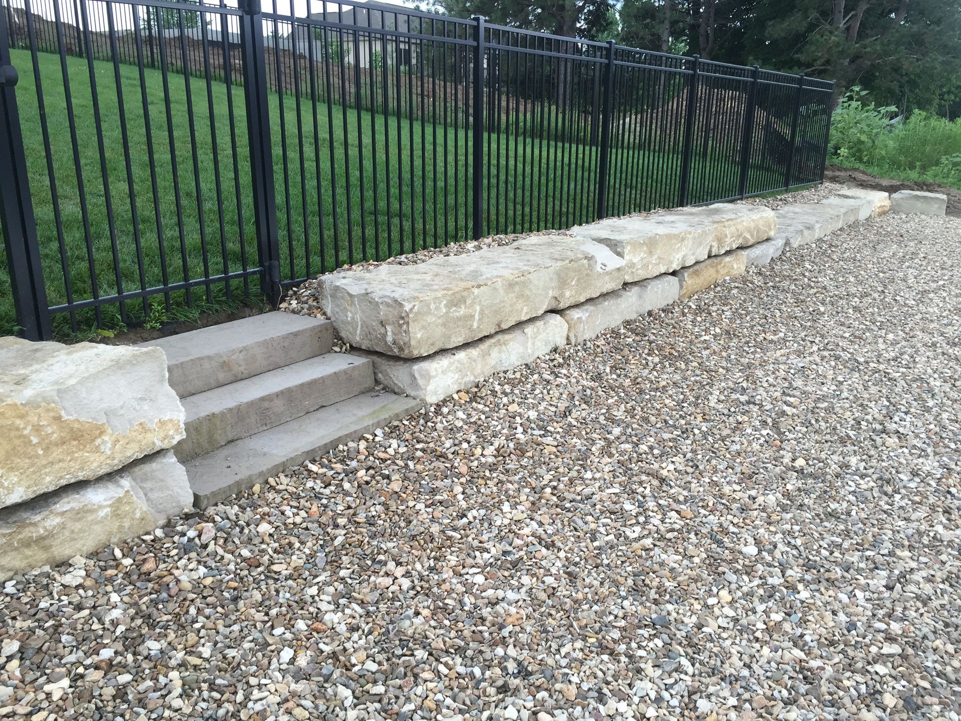 A gravel driveway with steps and a fence in the background.