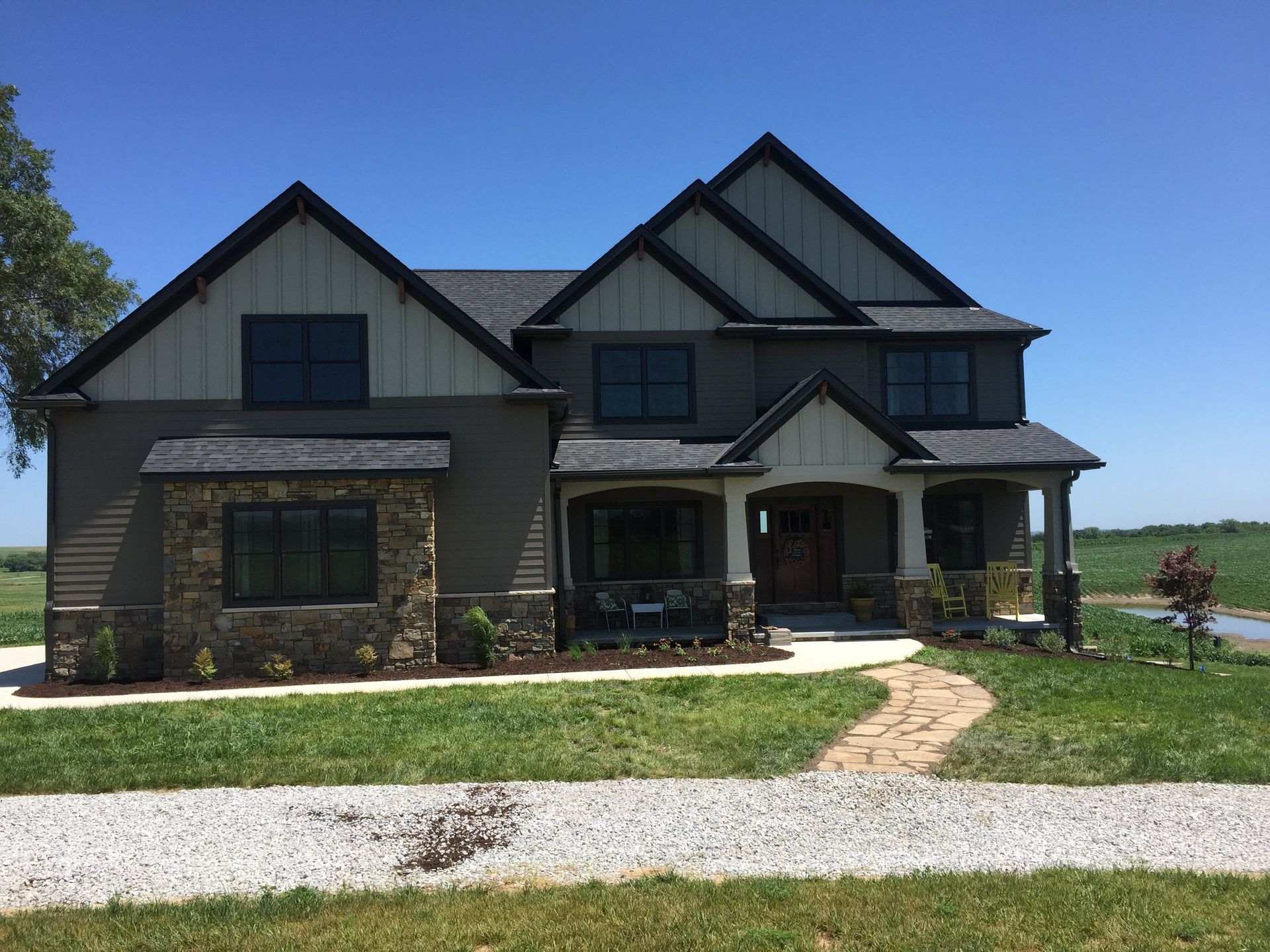 A large house with a lot of windows is sitting on top of a lush green field.