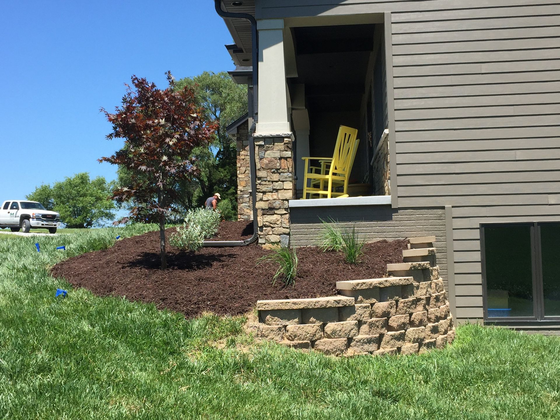 A yellow rocking chair is sitting on the porch of a house.