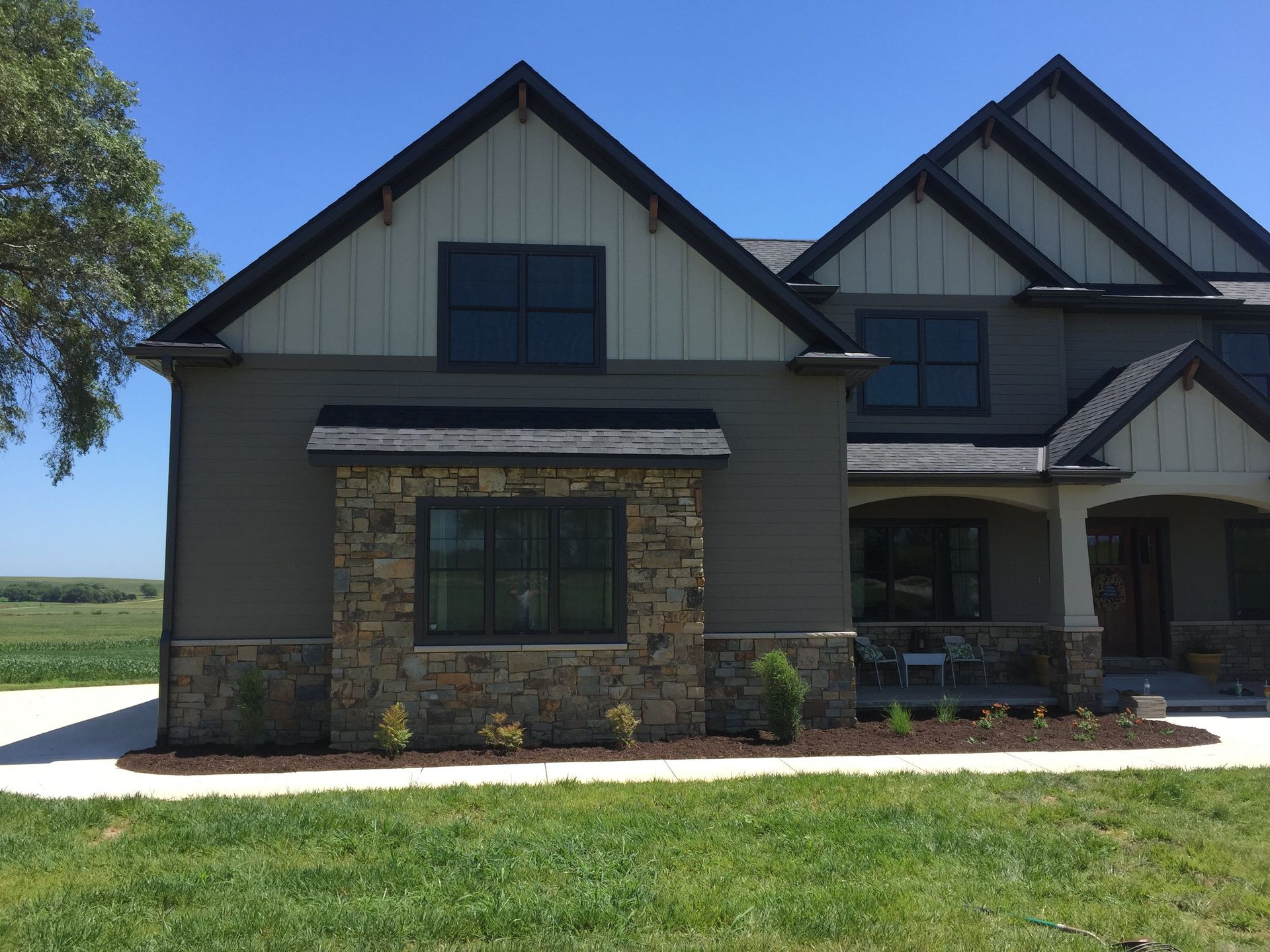 A large house with a lot of windows is sitting on top of a lush green field.