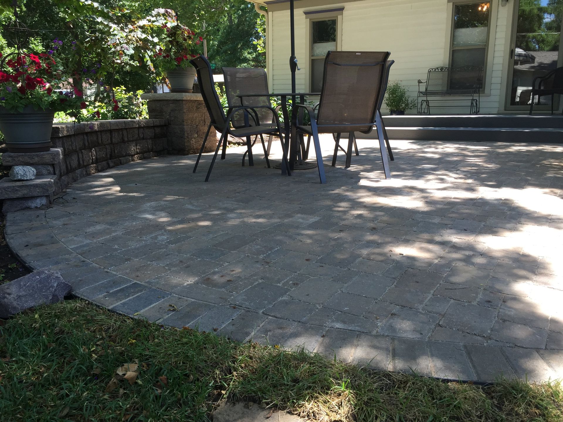 A patio with a table and chairs and an umbrella in front of a house.