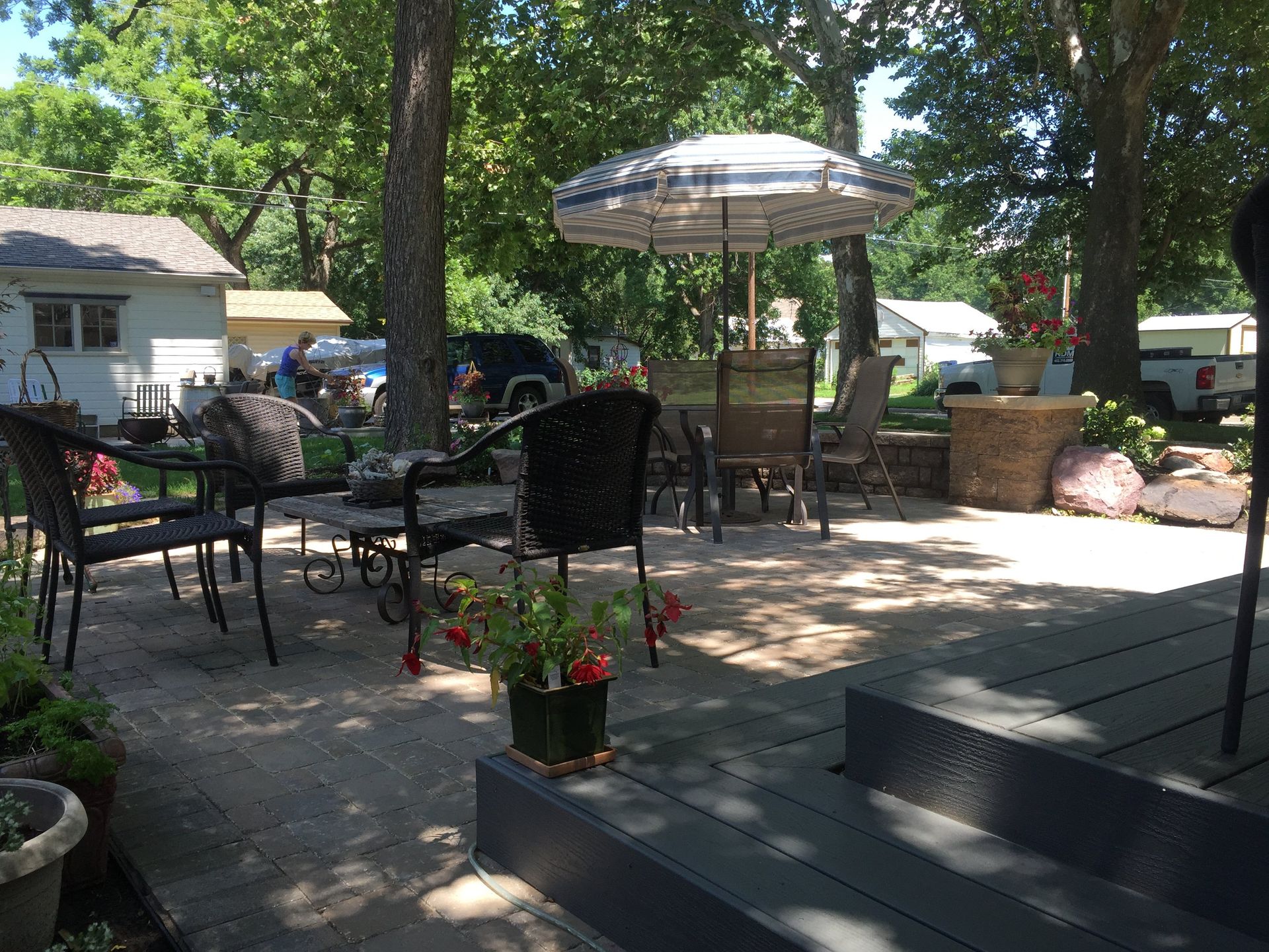A patio with a table , chairs , and umbrella on a sunny day.