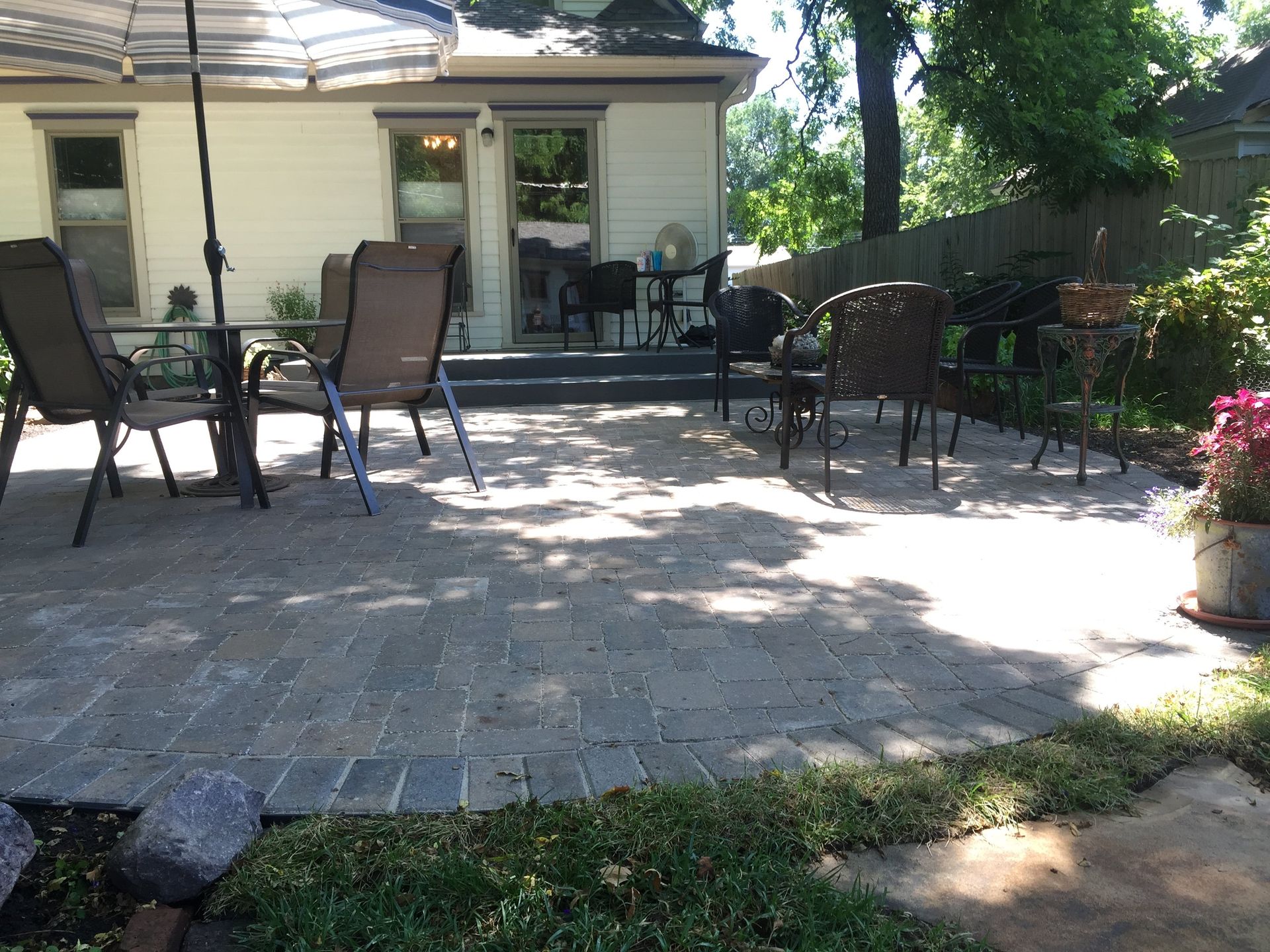 A patio with a table and chairs and an umbrella in front of a house.