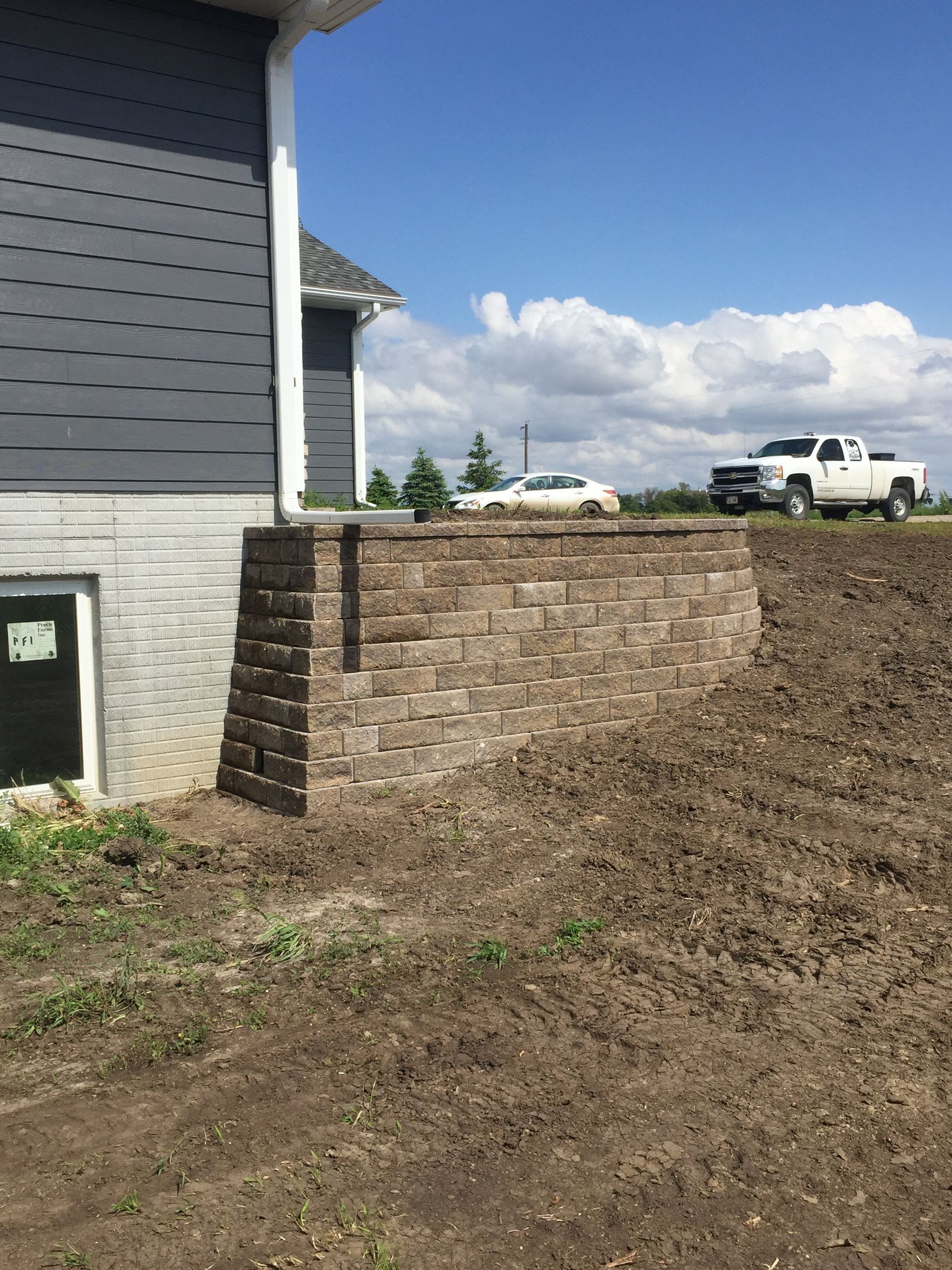 A brick wall is being built in front of a house.