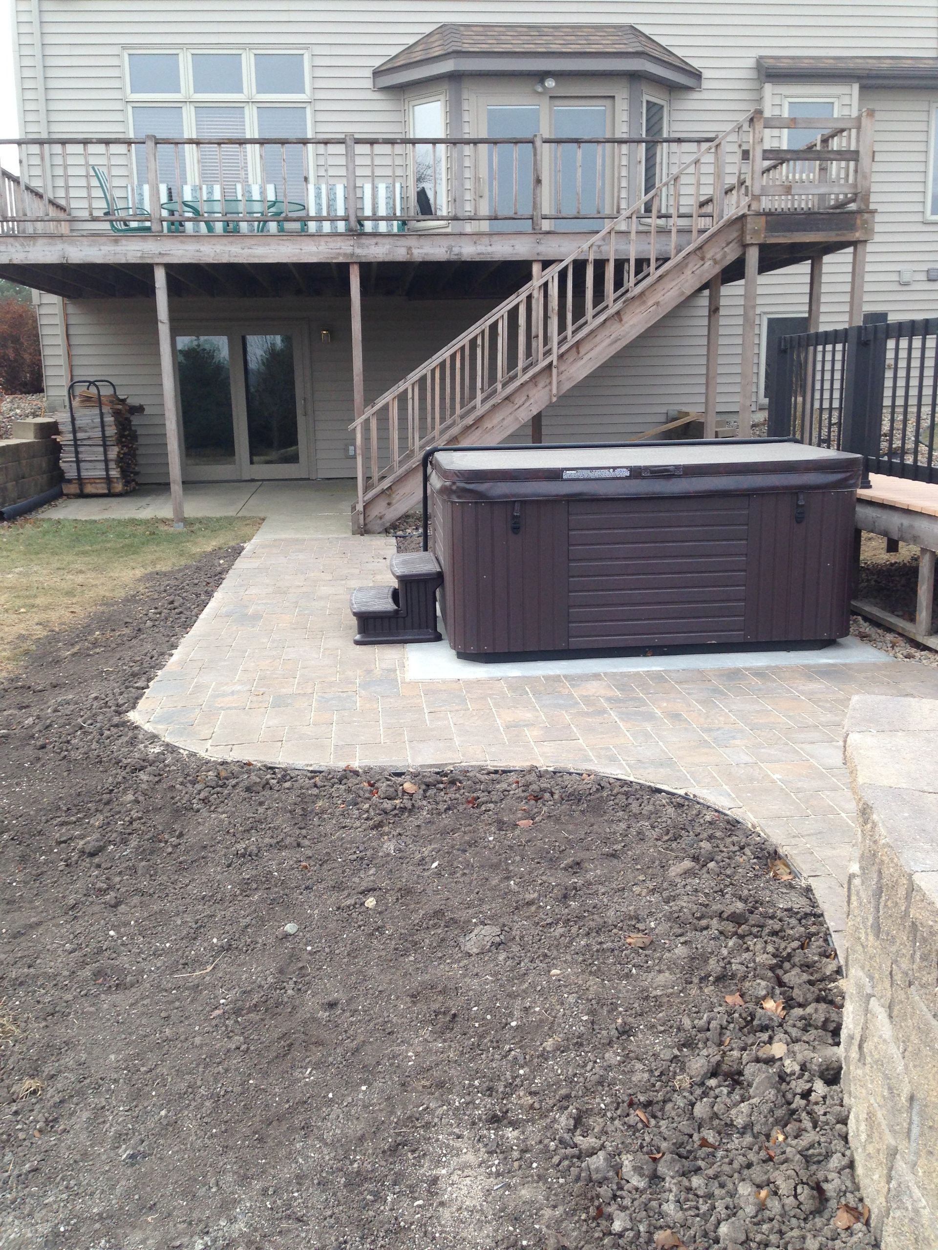 A hot tub is sitting on a patio in front of a house.