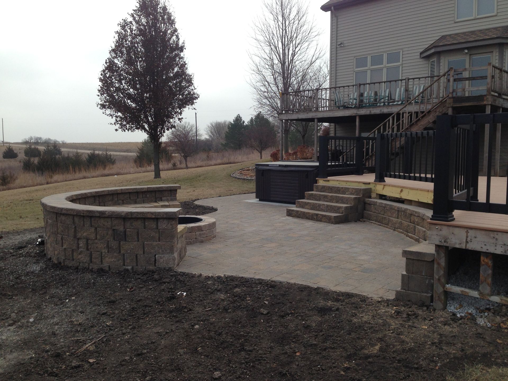 A patio with a fire pit and stairs in front of a house