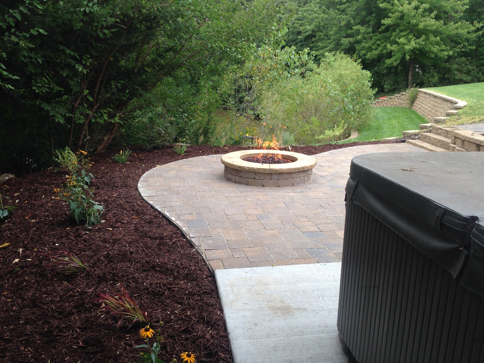 A fire pit is in the middle of a patio next to a hot tub.