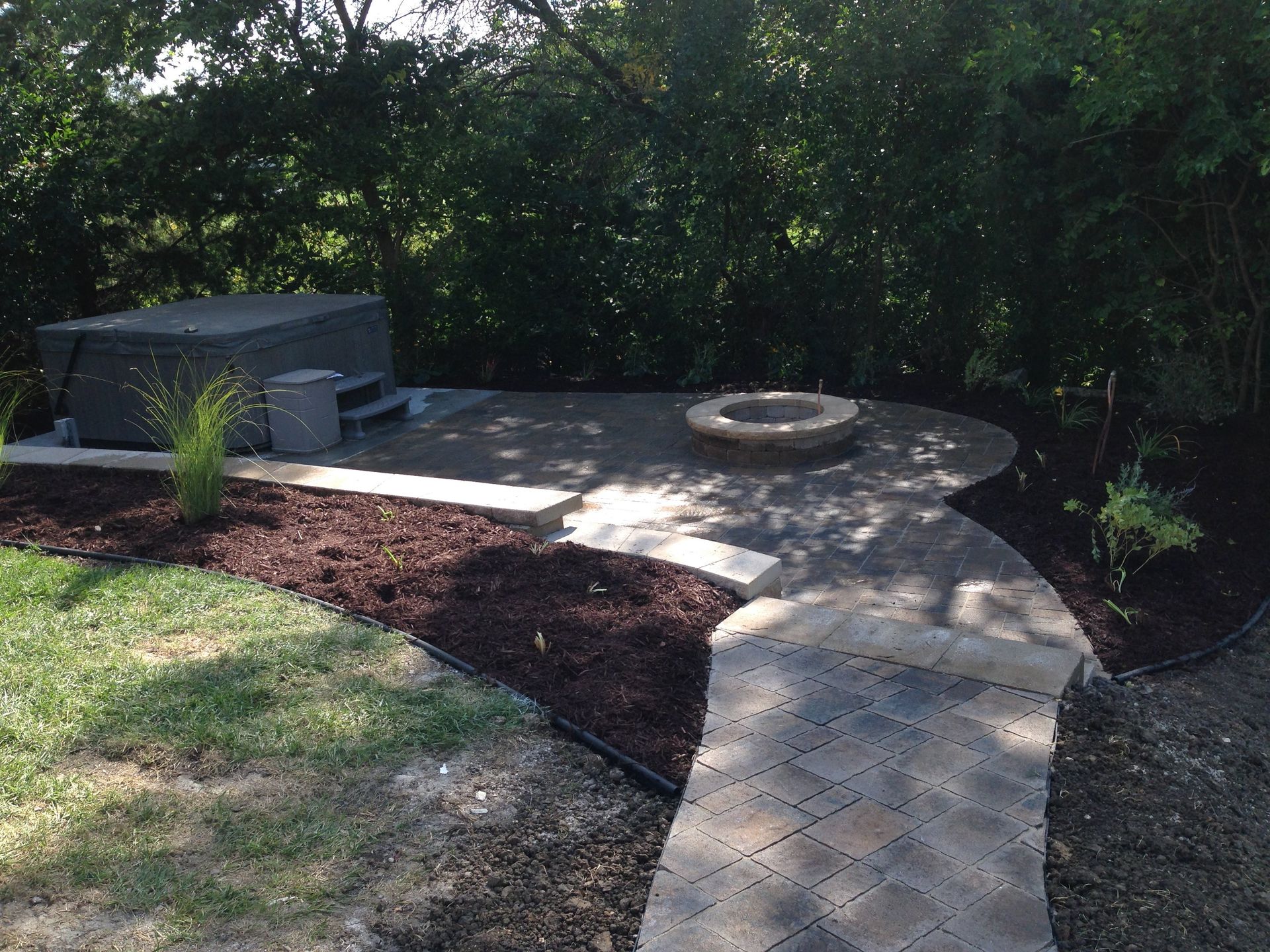 A patio with a hot tub and a fire pit