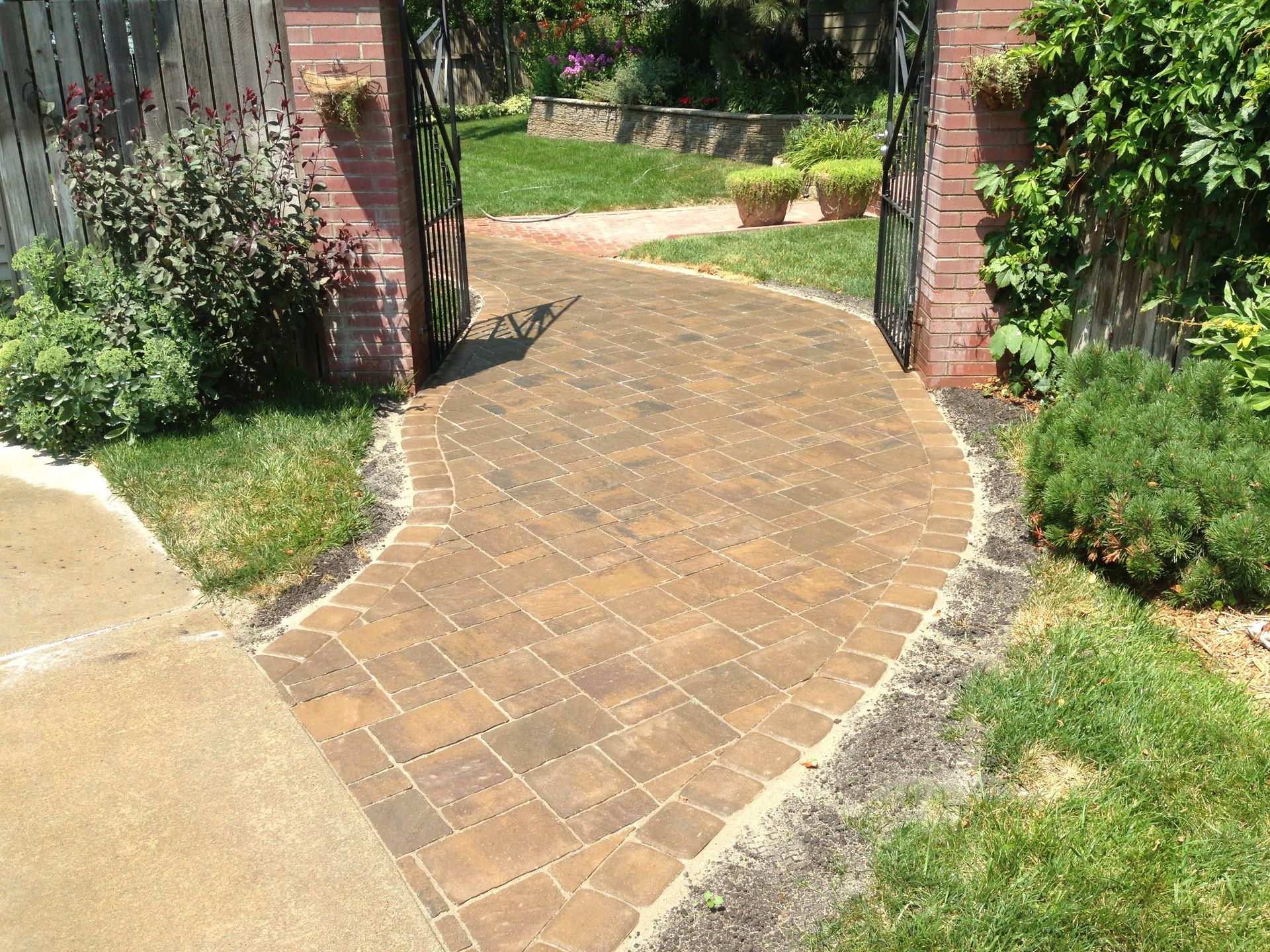 A brick walkway leading to a gate in a yard.