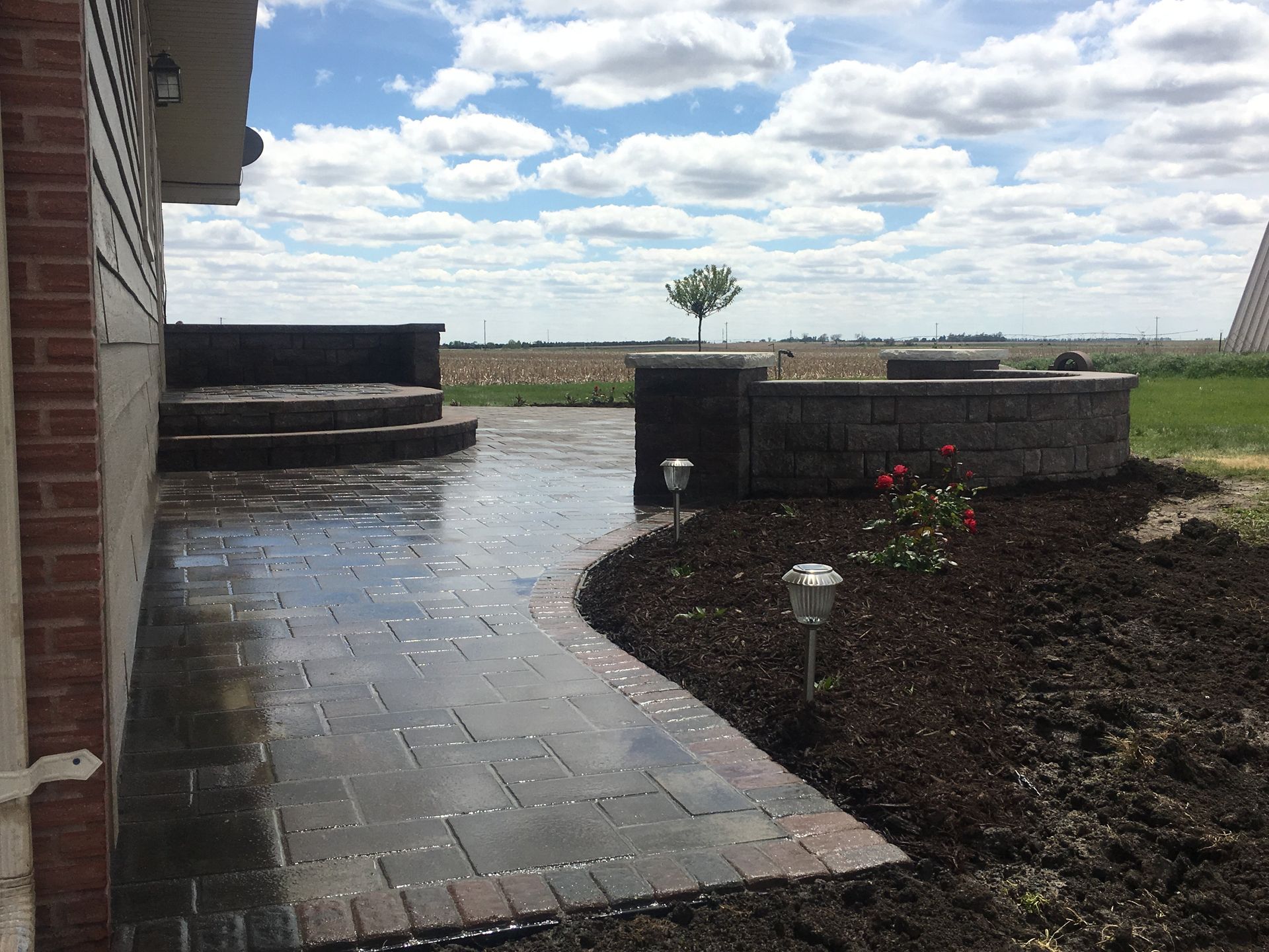 A brick walkway leading to a patio next to a brick building.
