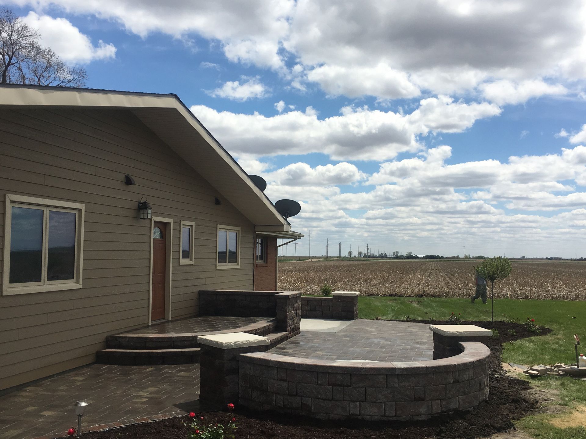 A house with a patio in front of it and a field in the background.