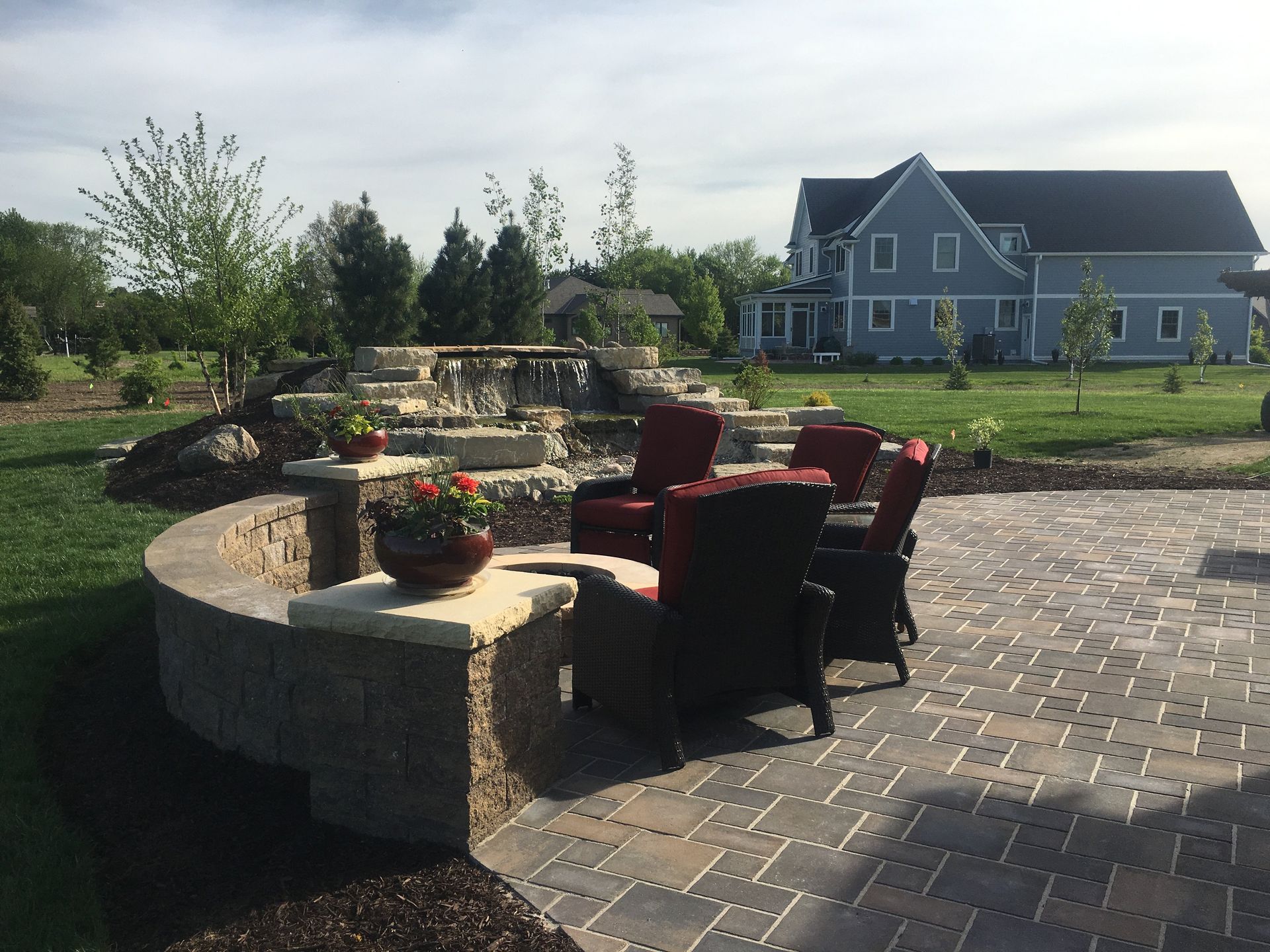 A patio with chairs and a table in front of a house.