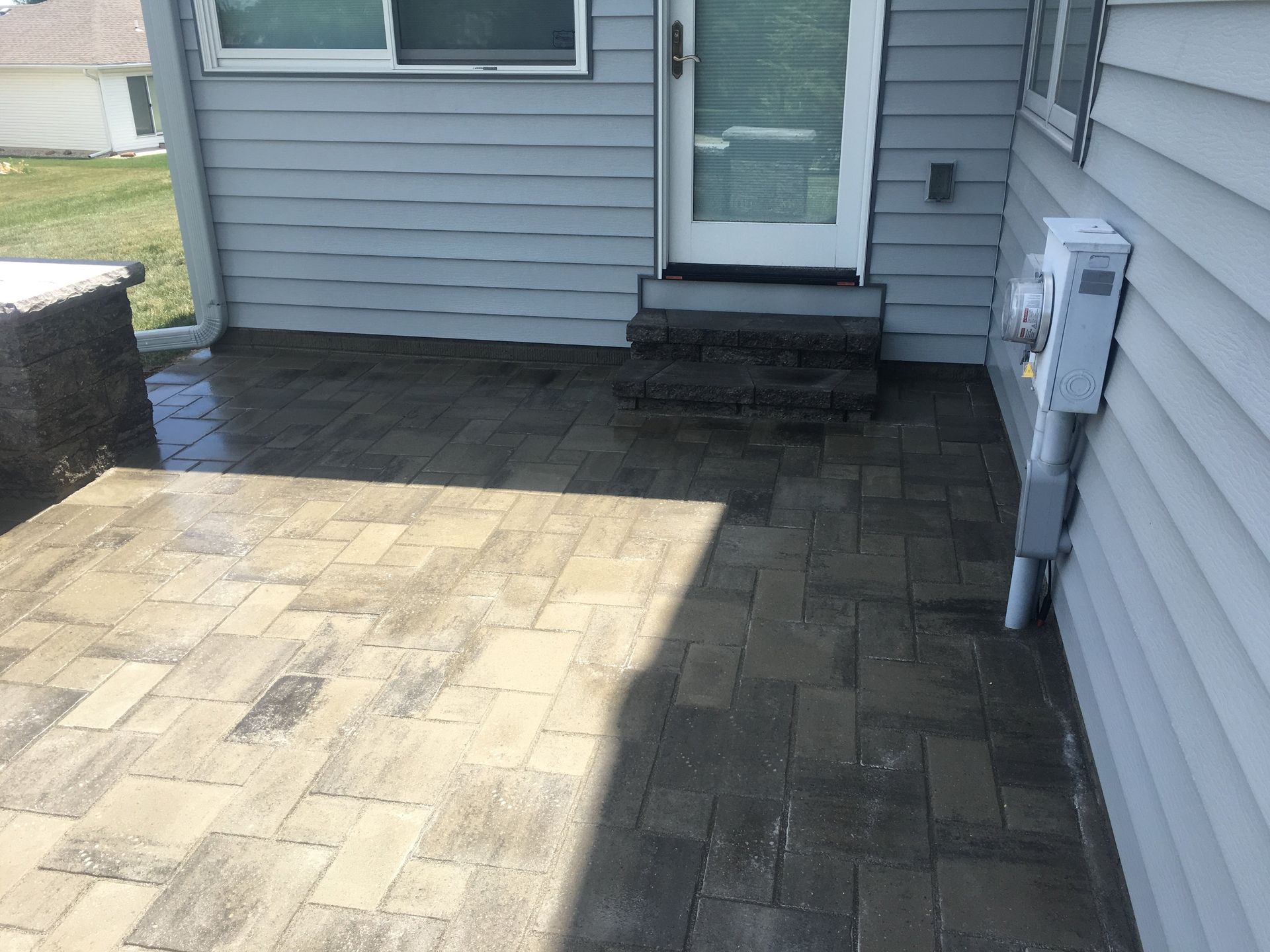 A patio in front of a house with a sliding glass door.