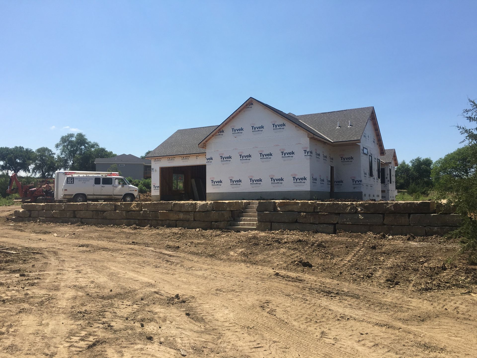 A white truck is parked in front of a house under construction.