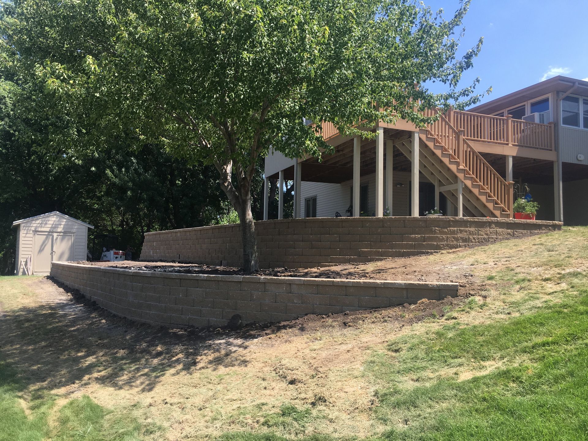 A house with a large deck and stairs is sitting on top of a hill.