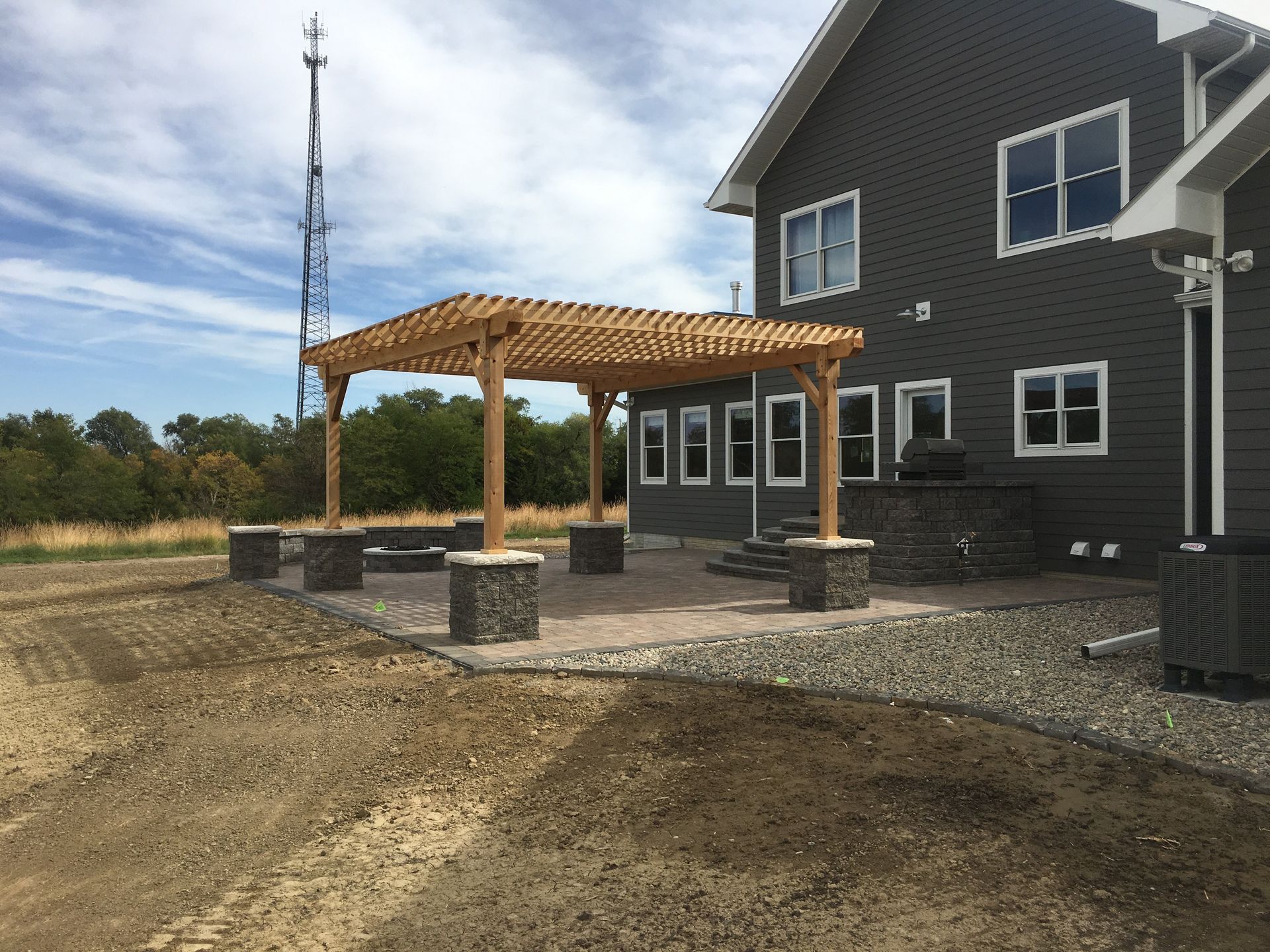 A large gray house with a wooden pergola in front of it.