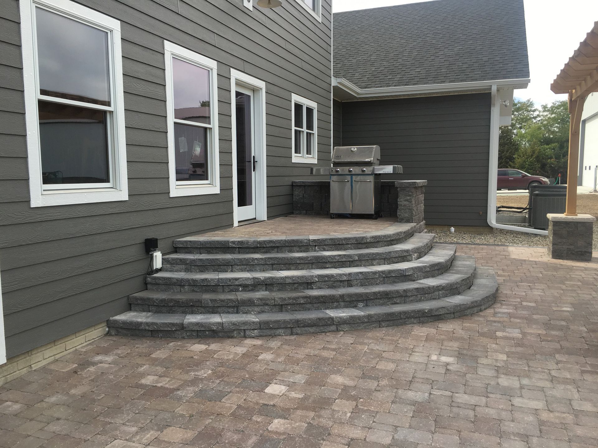 A patio with stairs and a grill in front of a house.