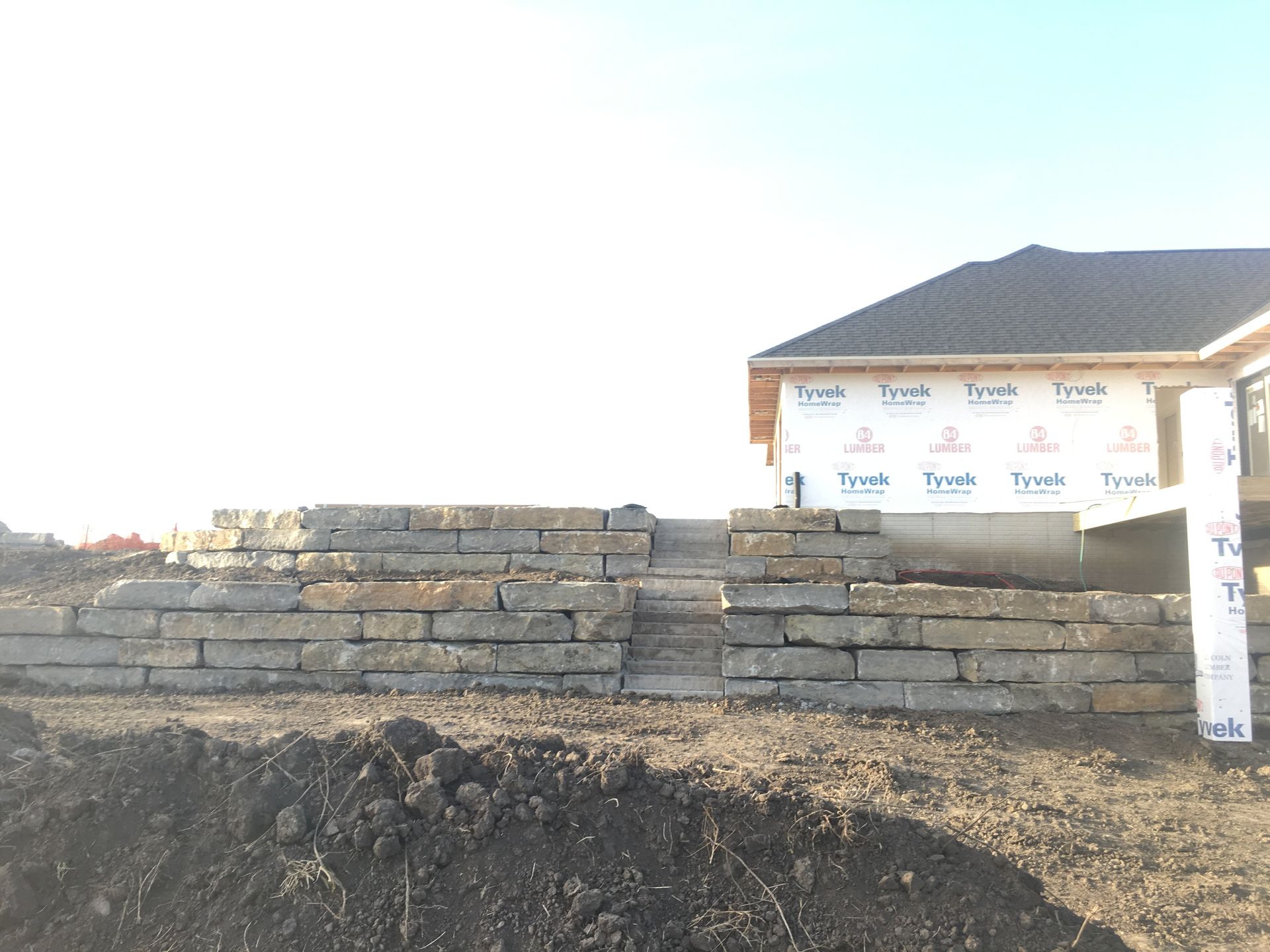 A large pile of dirt is in front of a house under construction.