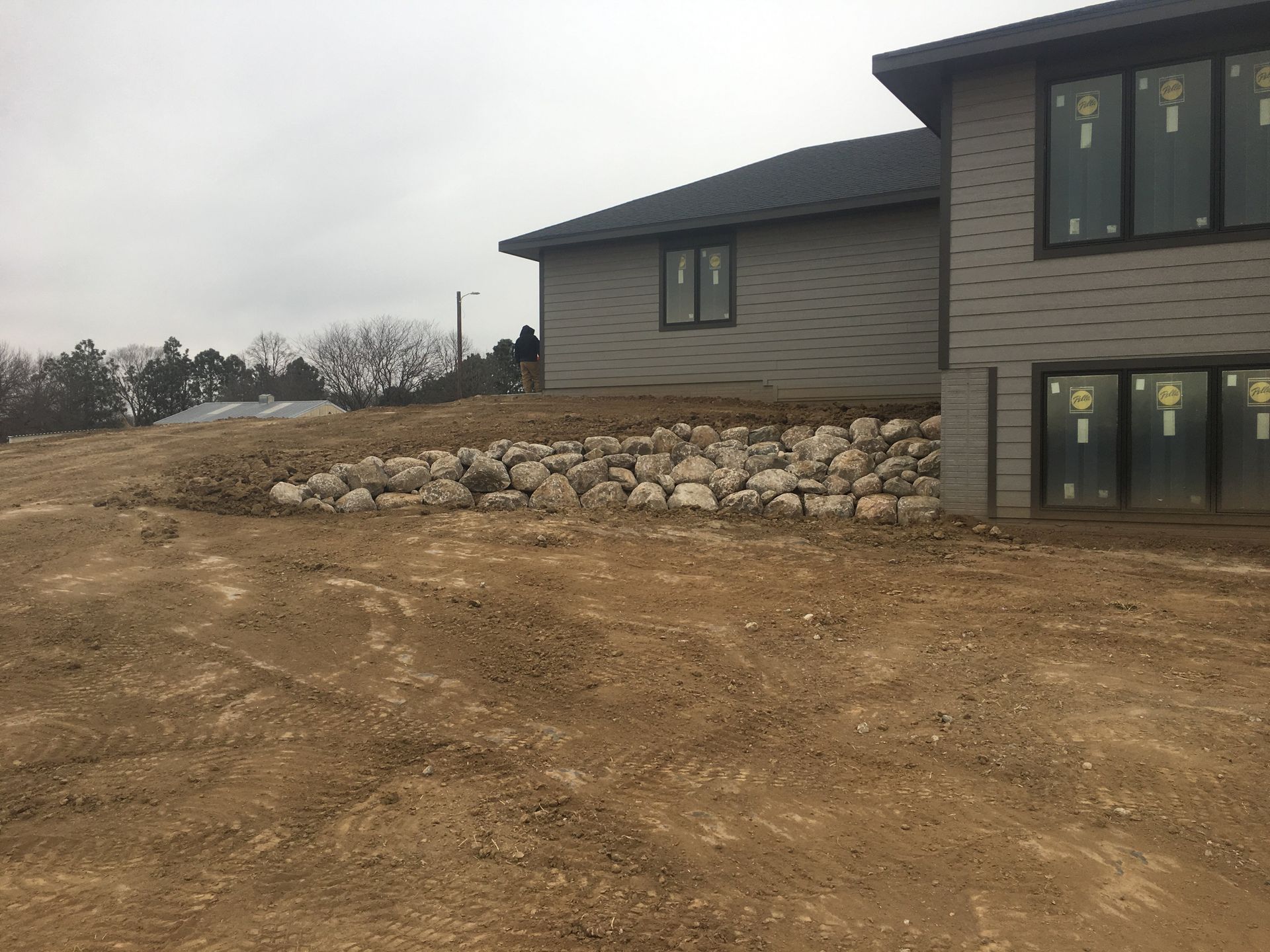 A large house is sitting on top of a dirt hill.