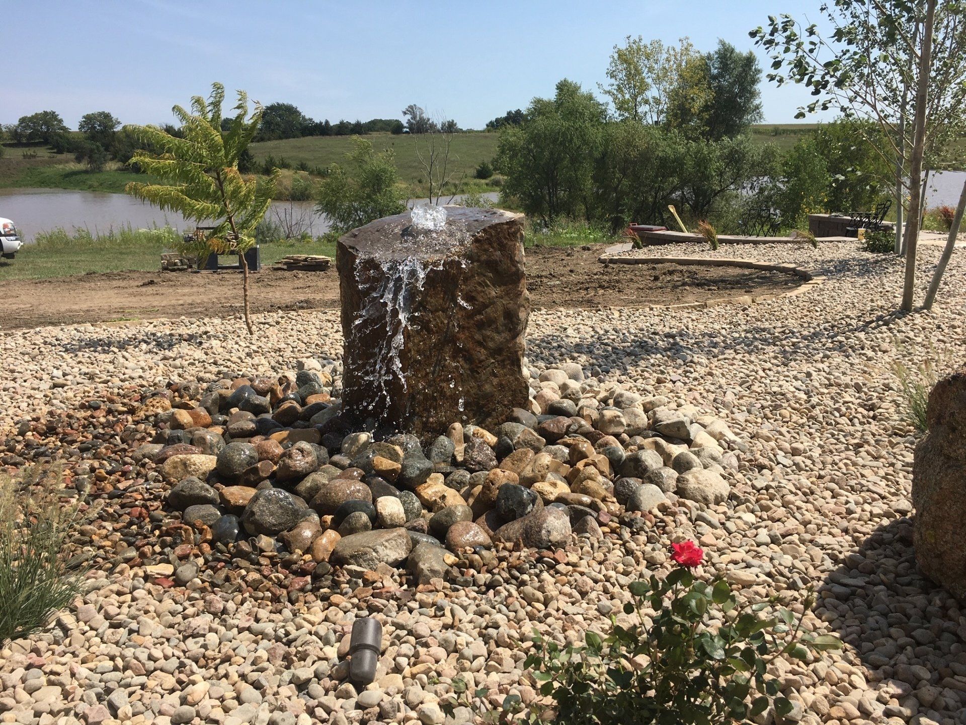 A water fountain is surrounded by rocks and gravel in a garden.