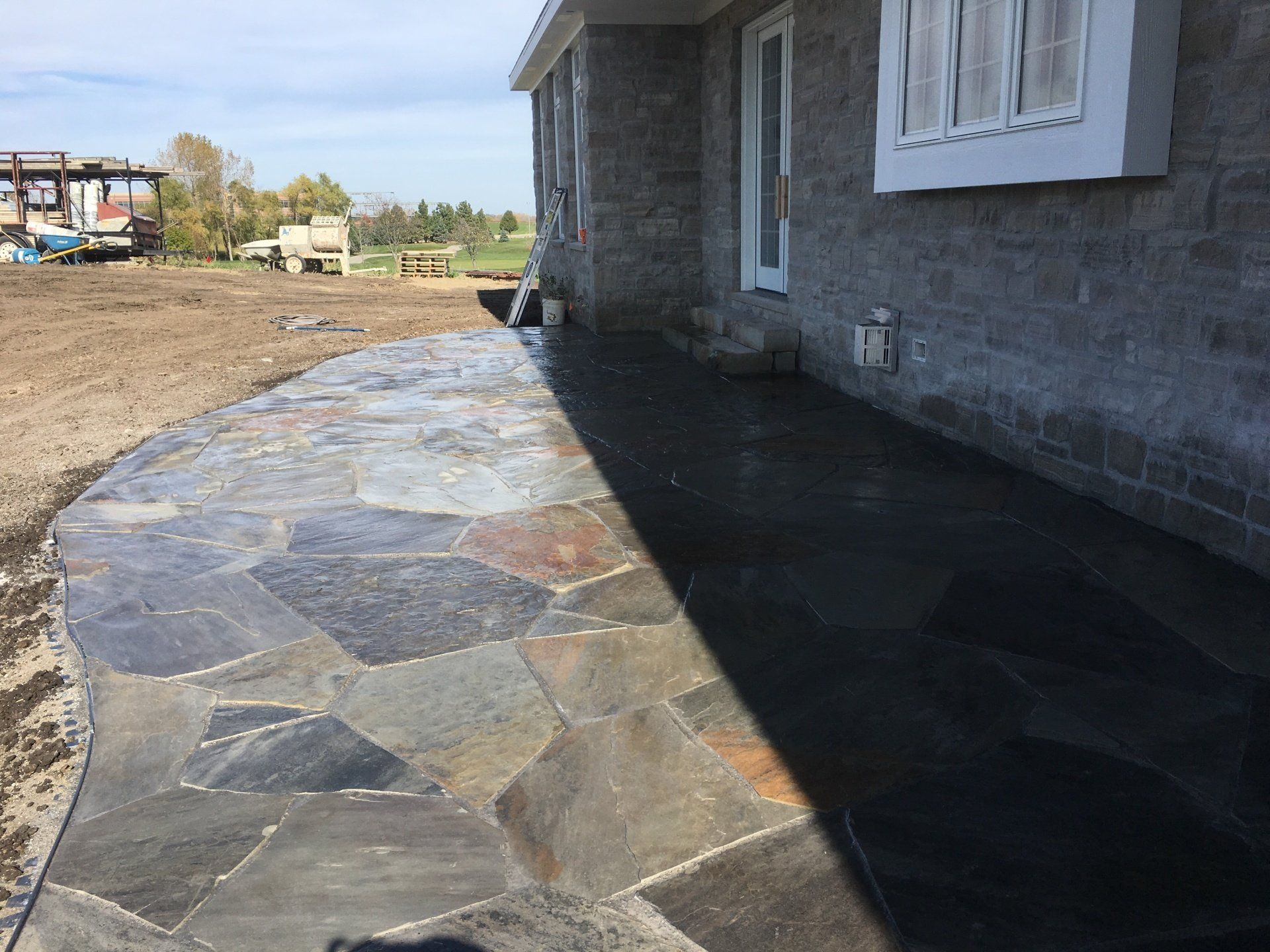 A stone walkway is being built in front of a brick house.