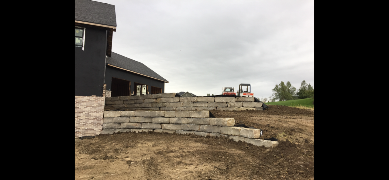 A large brick wall is being built in front of a house.