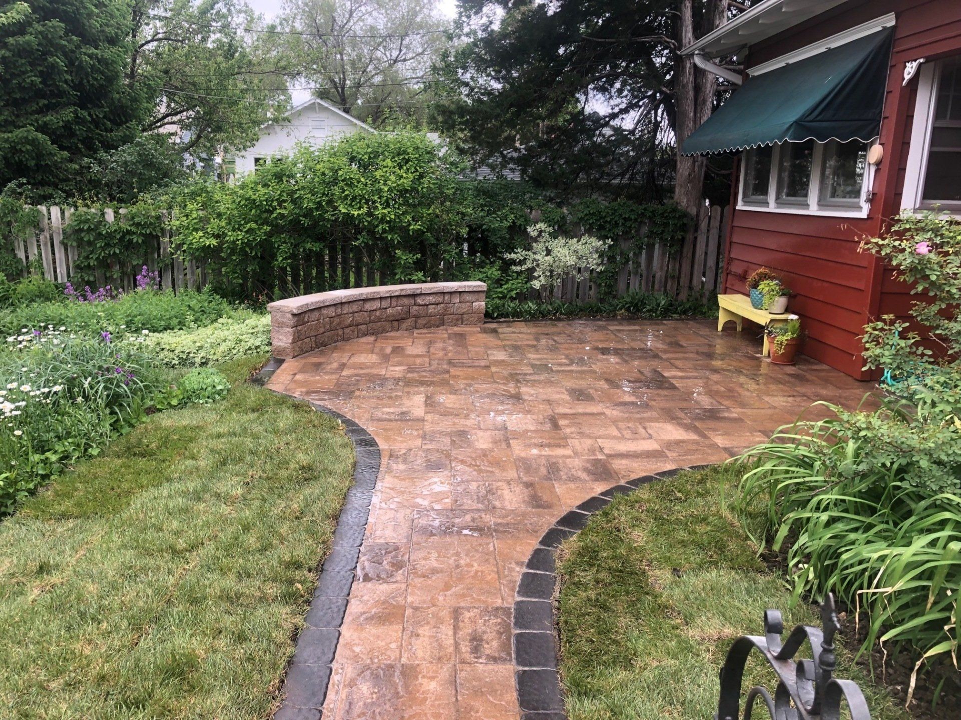 There is a walkway leading to a patio in the backyard of a house.
