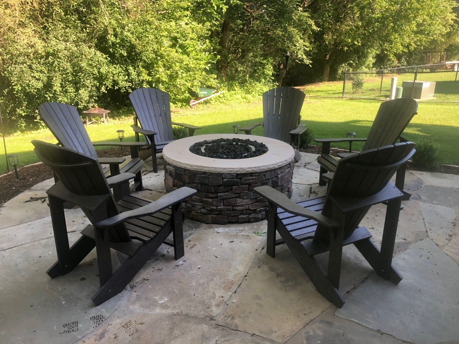 A group of chairs are sitting around a fire pit on a patio.