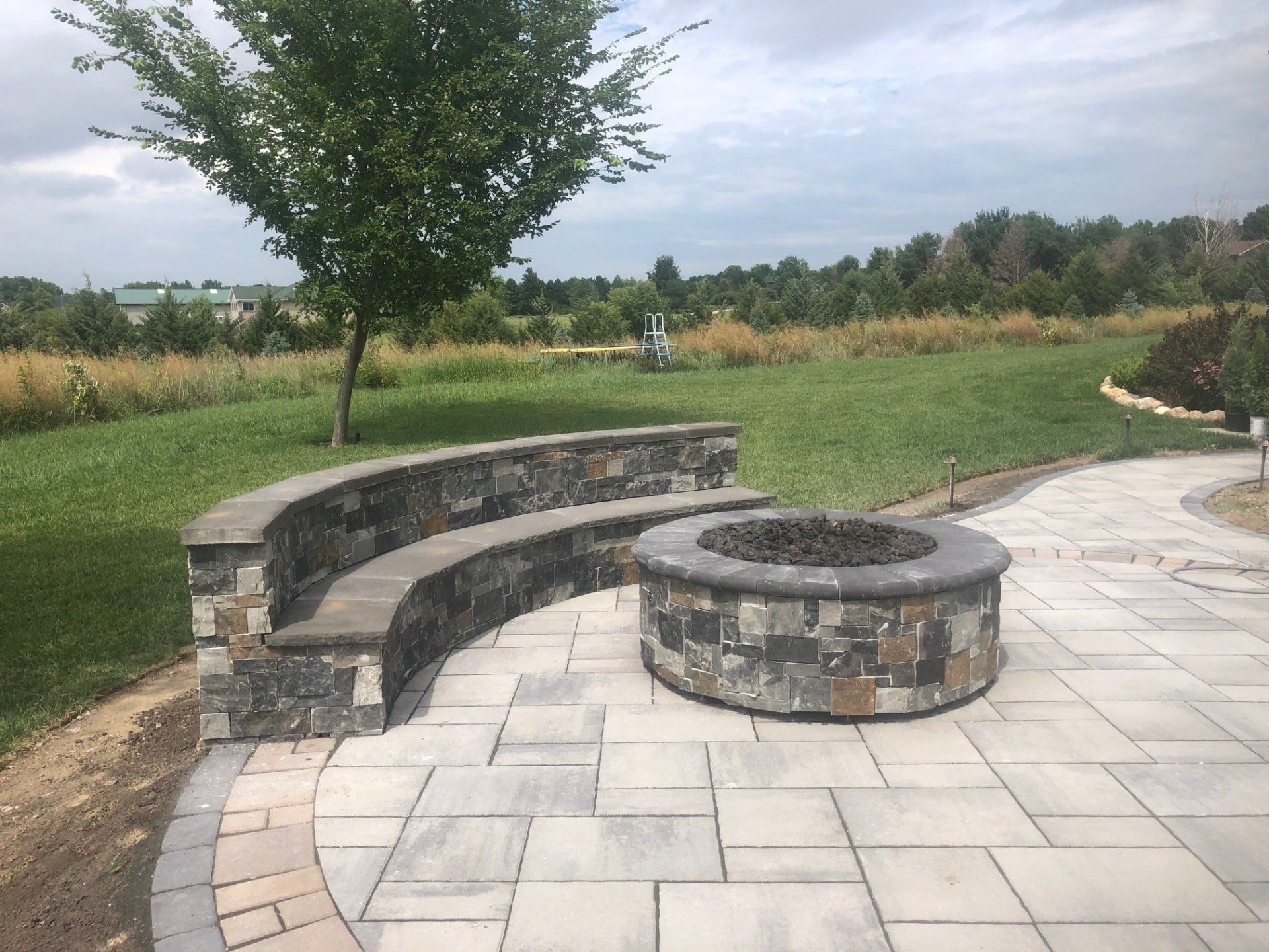 A patio with a fire pit and a stone wall