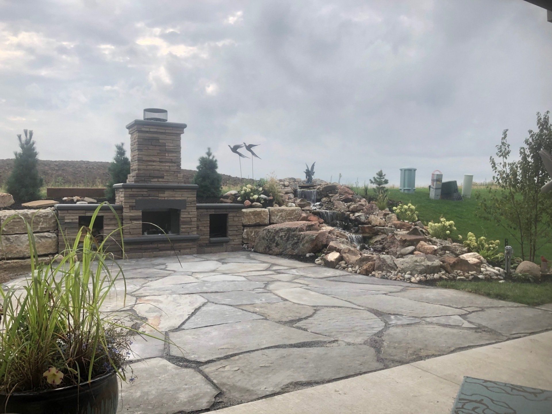 A patio with a fireplace and a waterfall in the background.