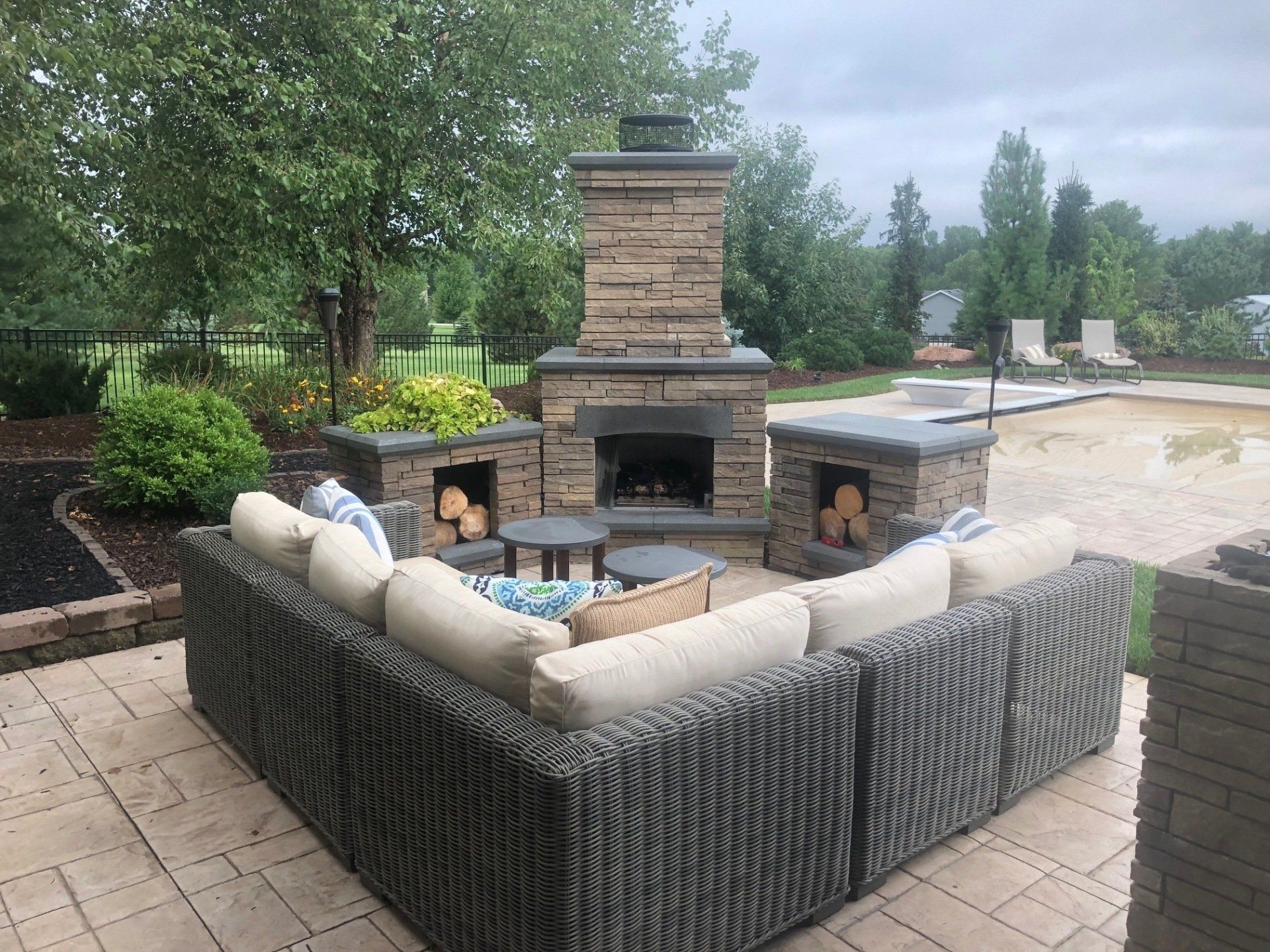 A patio with a fireplace and a sectional couch.