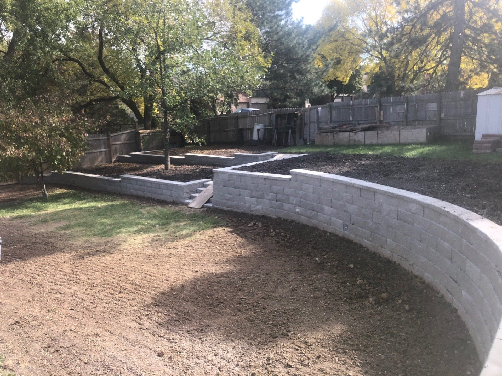 A brick wall is being built in the backyard of a house.