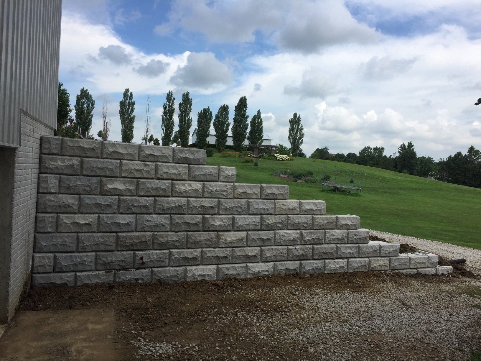 A brick wall is being built next to a grassy field.