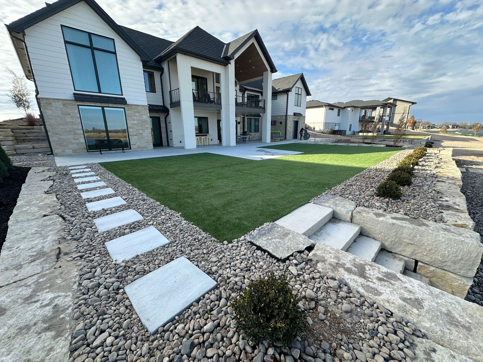 Luxury house with stone landscaping, stepping stones, and green lawn.