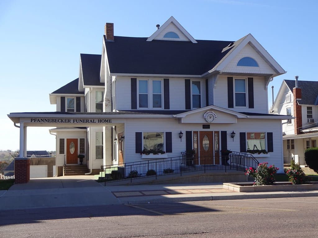 A large white house with black shutters and a sign that says passengers memorial