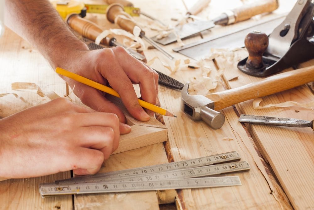 Hands Measuring Wood With a Pencil and Ruler on a Workbench — C K Carpentry in Byron Bay, NSW