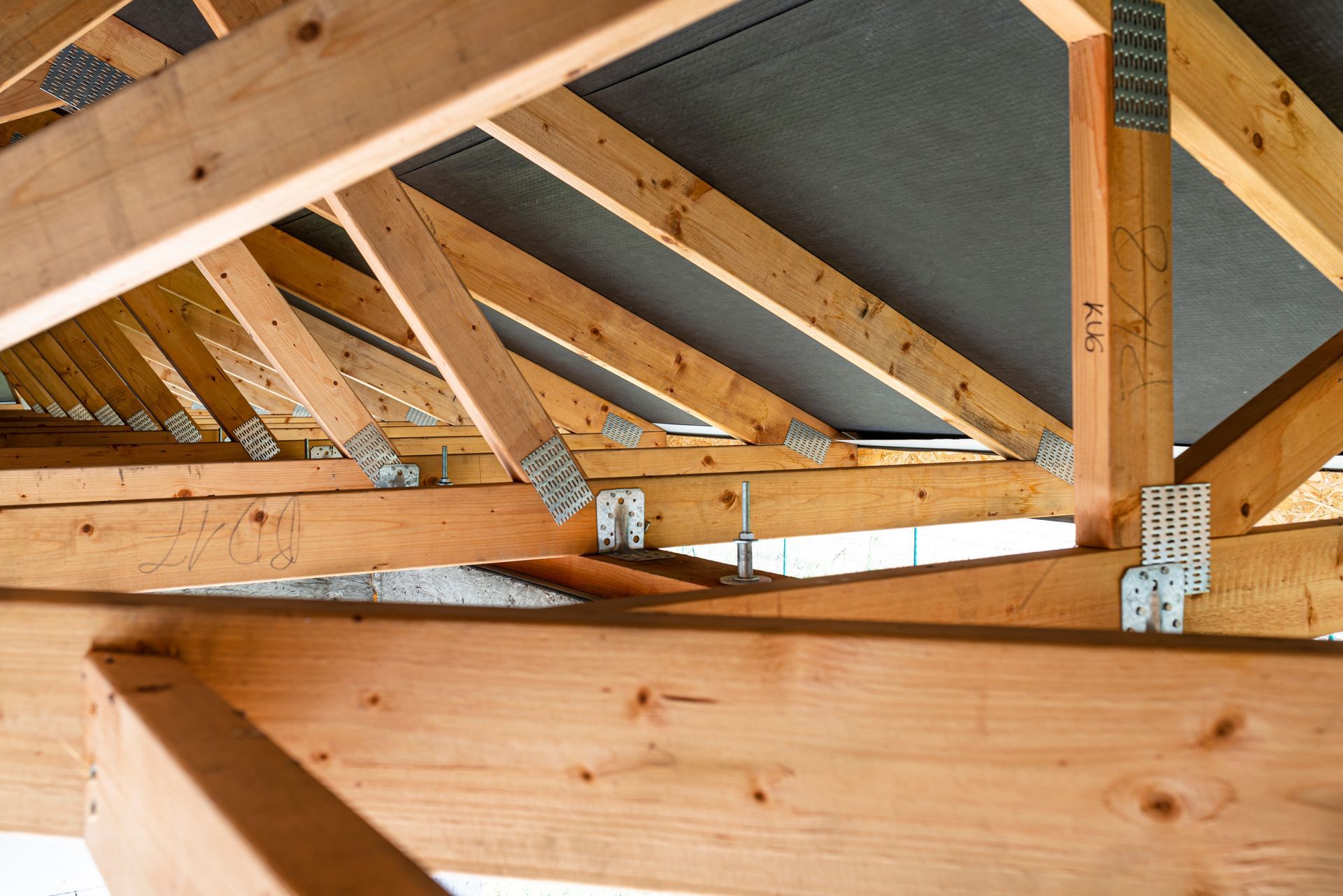 Wooden Roof Trusses With Metal Connectors Inside an Unfinished Attic Framing — C K Carpentry in Byron Bay, NSW