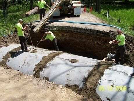 A group of men are working on a large pipe in the dirt.