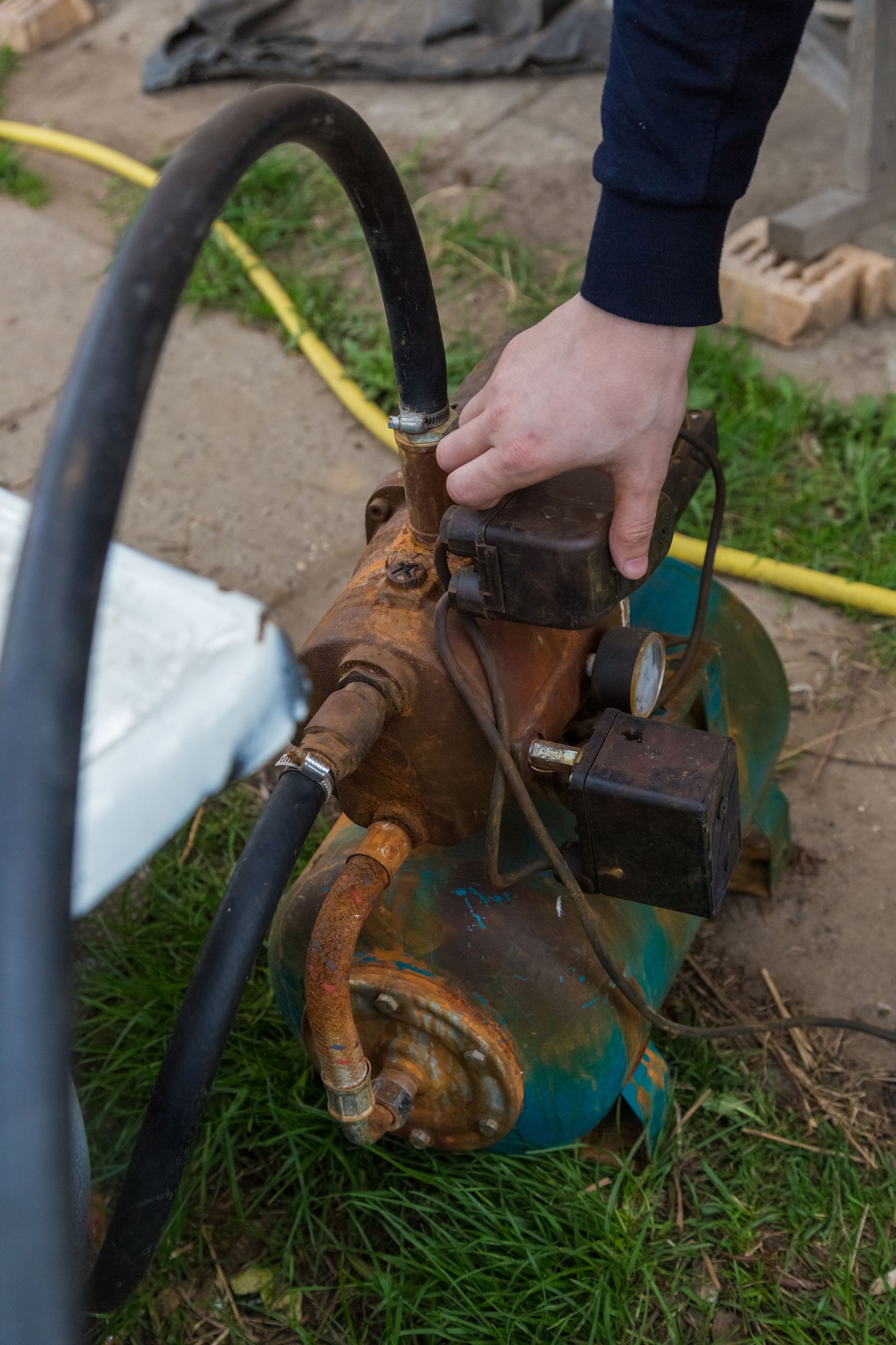 A close-up of a technician performing an emergency water pump repair on a rusted outdoor system.