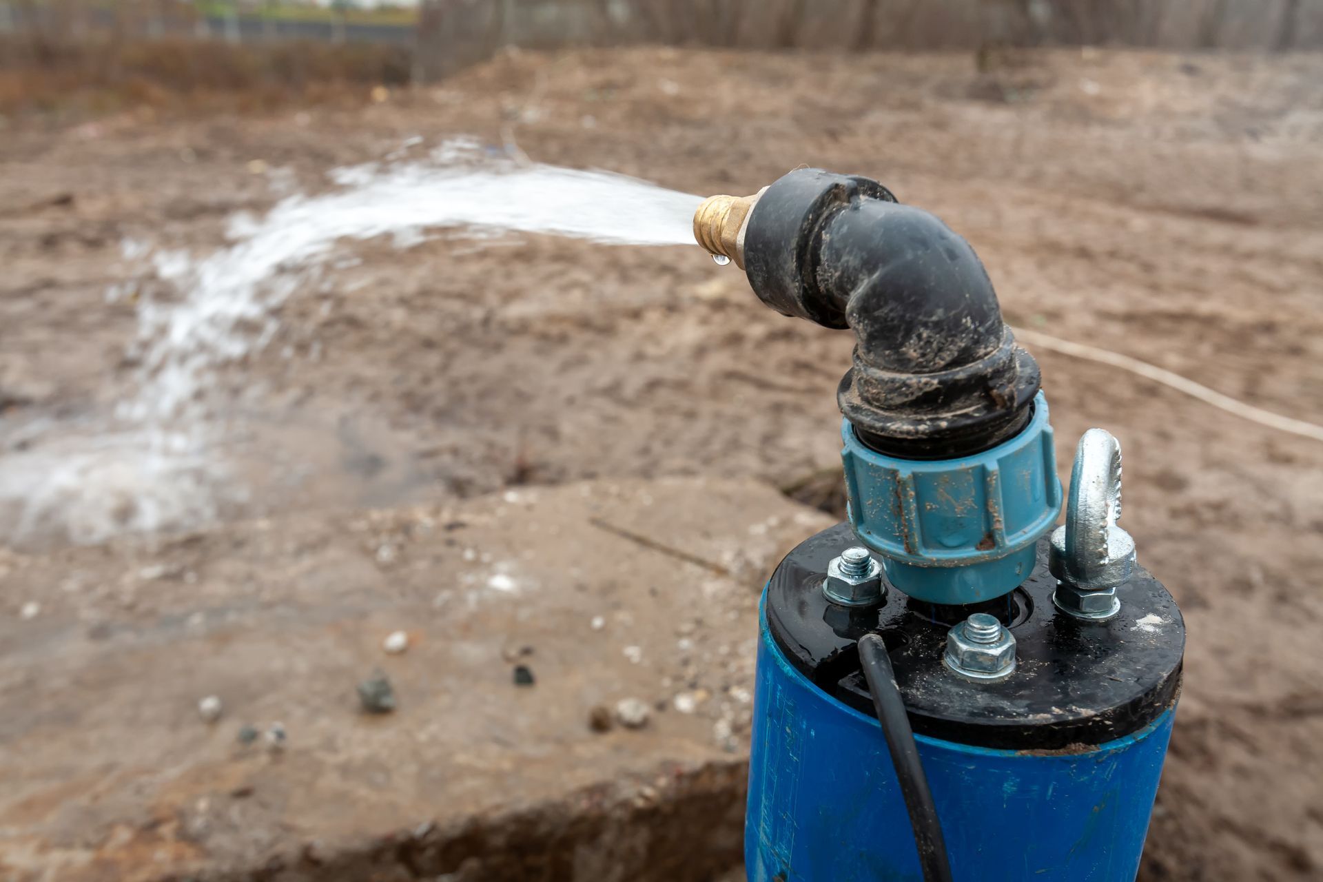 Close-up of a blue well pump head following an emergency well repair in a rural field.
