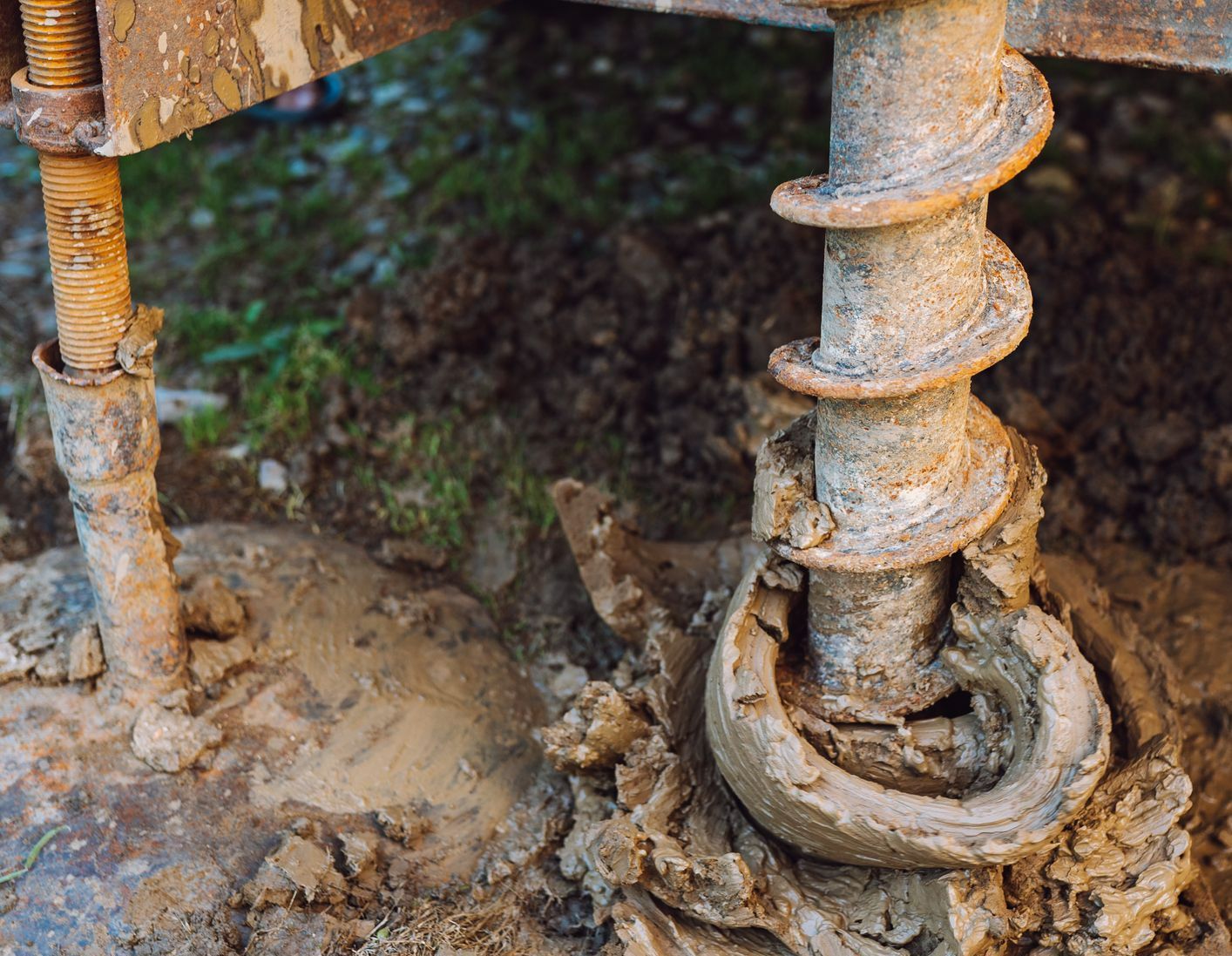 A close up of a drill bit in the ground.