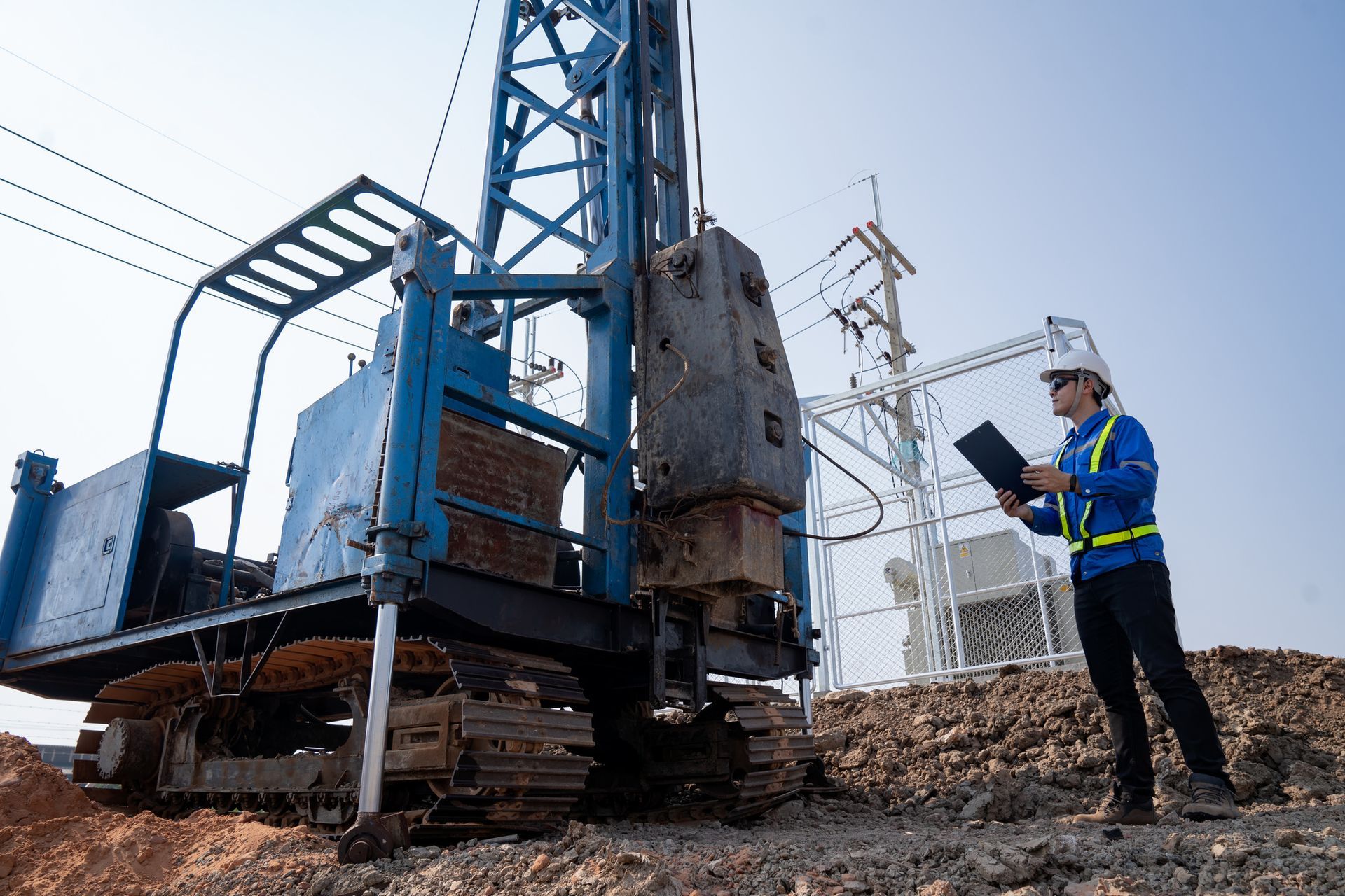 A construction worker is standing in front of a machine on a construction site.