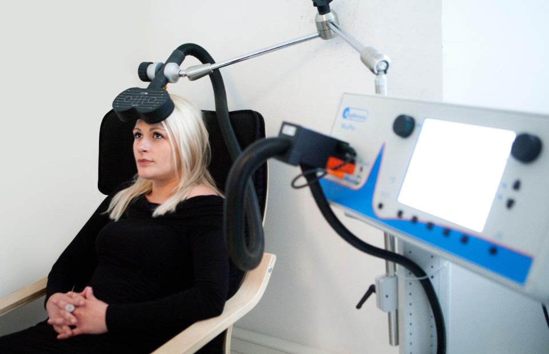 A woman is sitting in a chair in front of a machine.