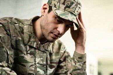 A man in a military uniform is holding his head with his hand.