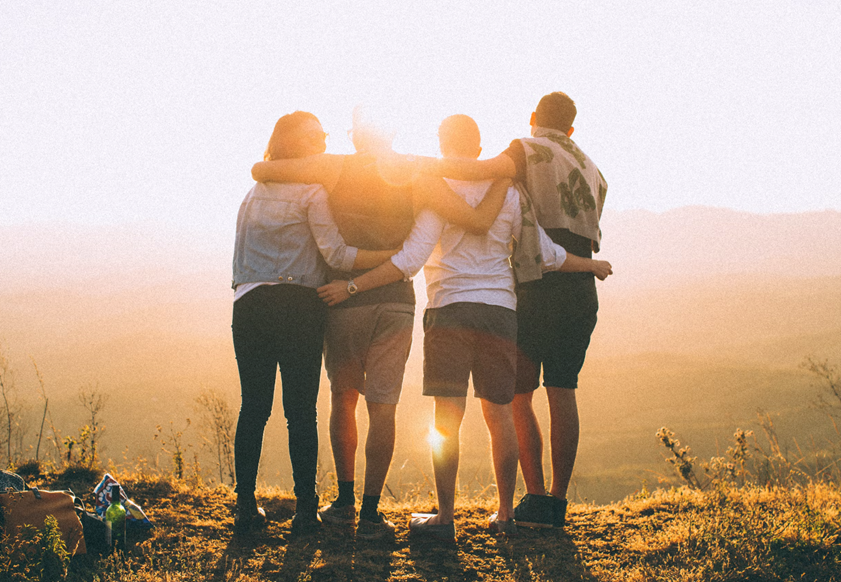 A group of people are hugging each other on top of a hill.