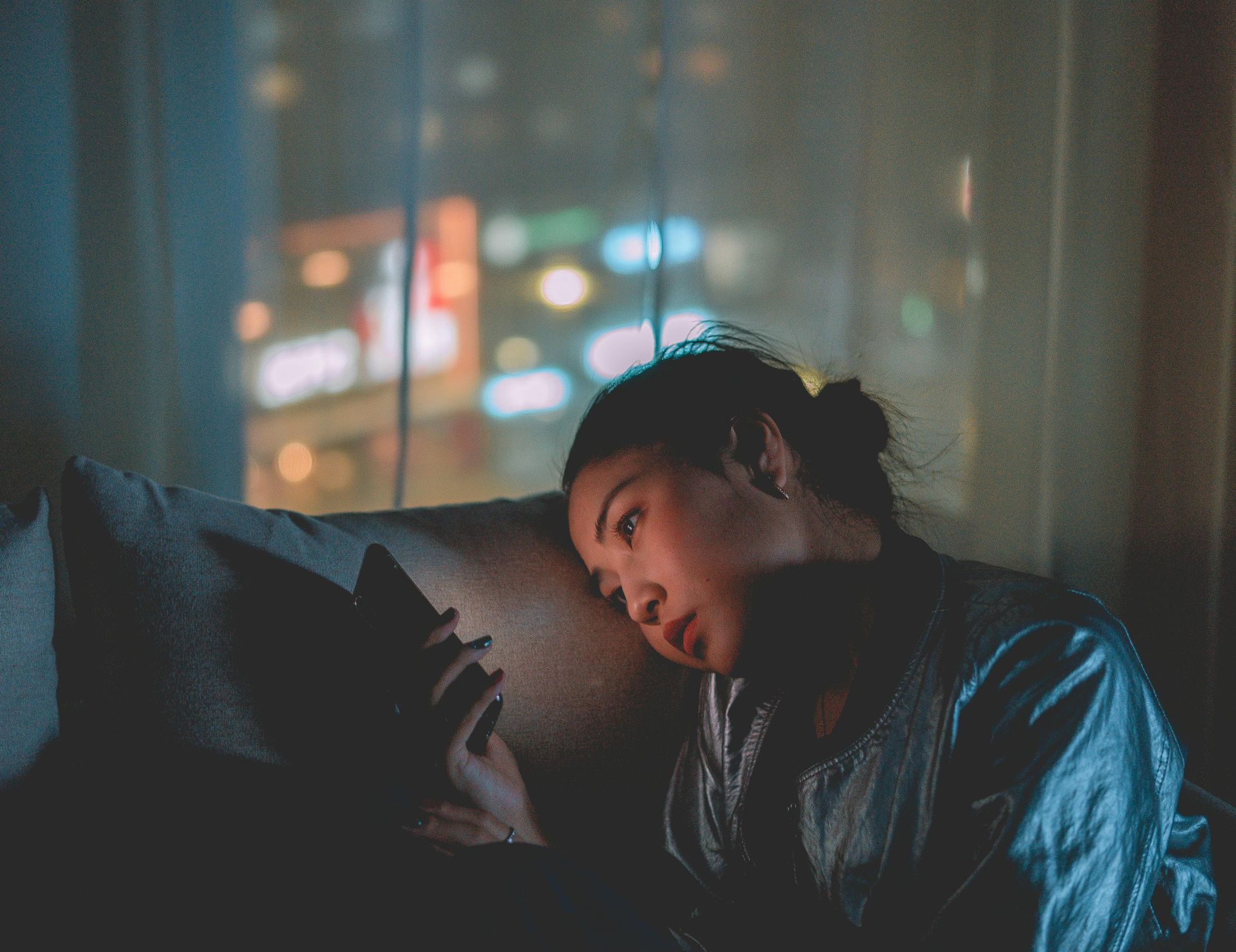 A woman is laying on a couch looking at her phone.