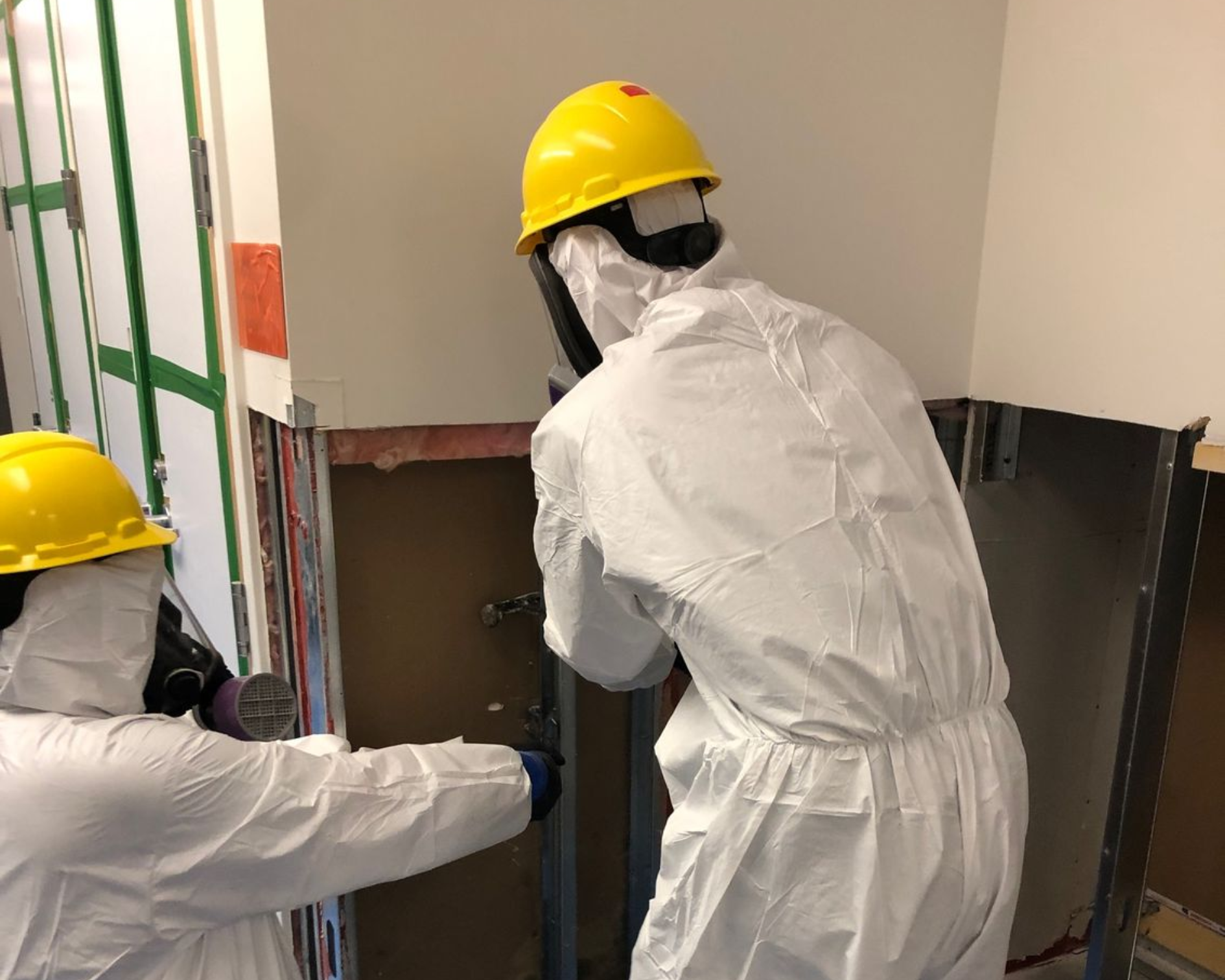 Un homme en combinaison de protection pulvérise du désinfectant dans un couloir.